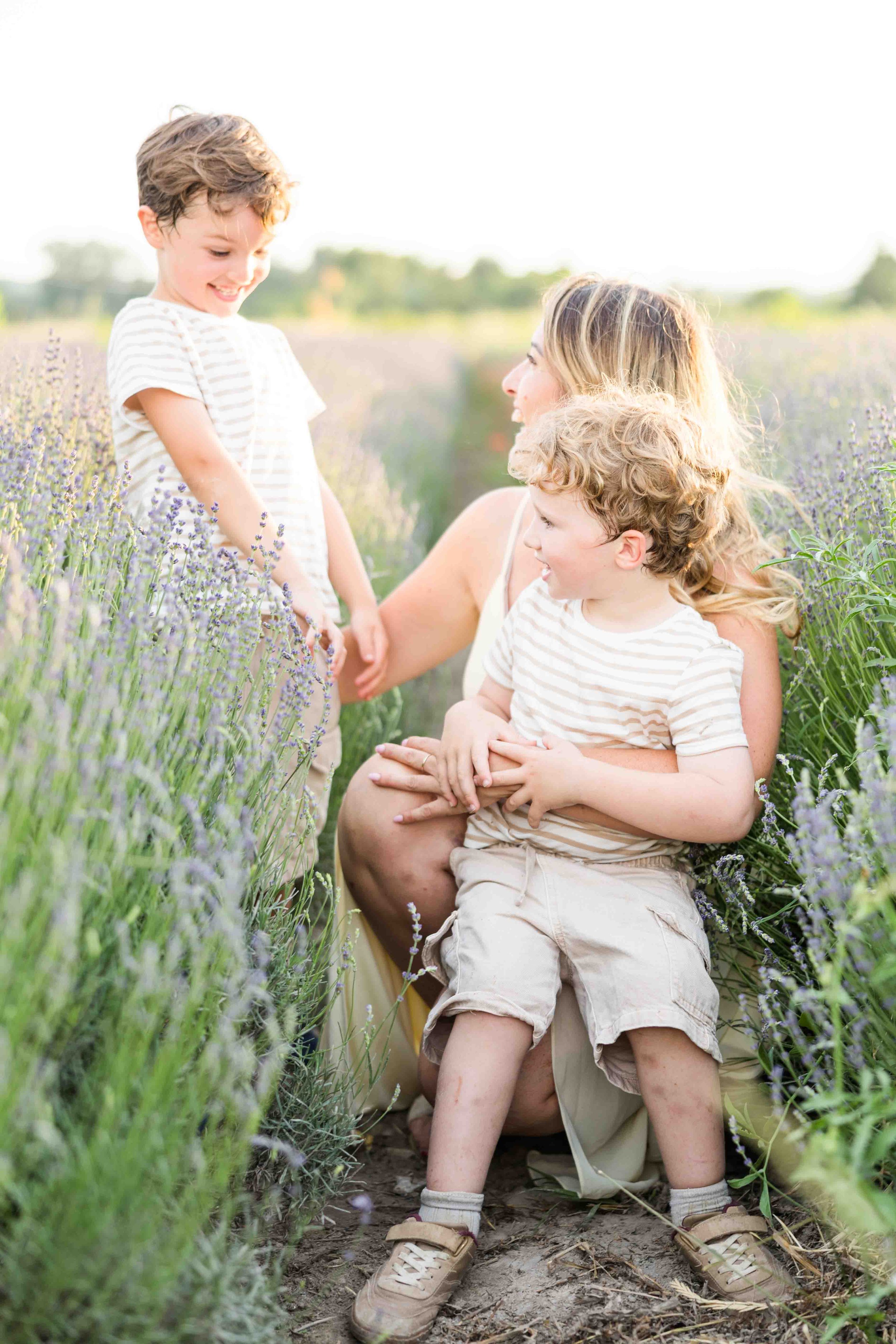 mom playing with her sons in a lavender in provence during golden hour