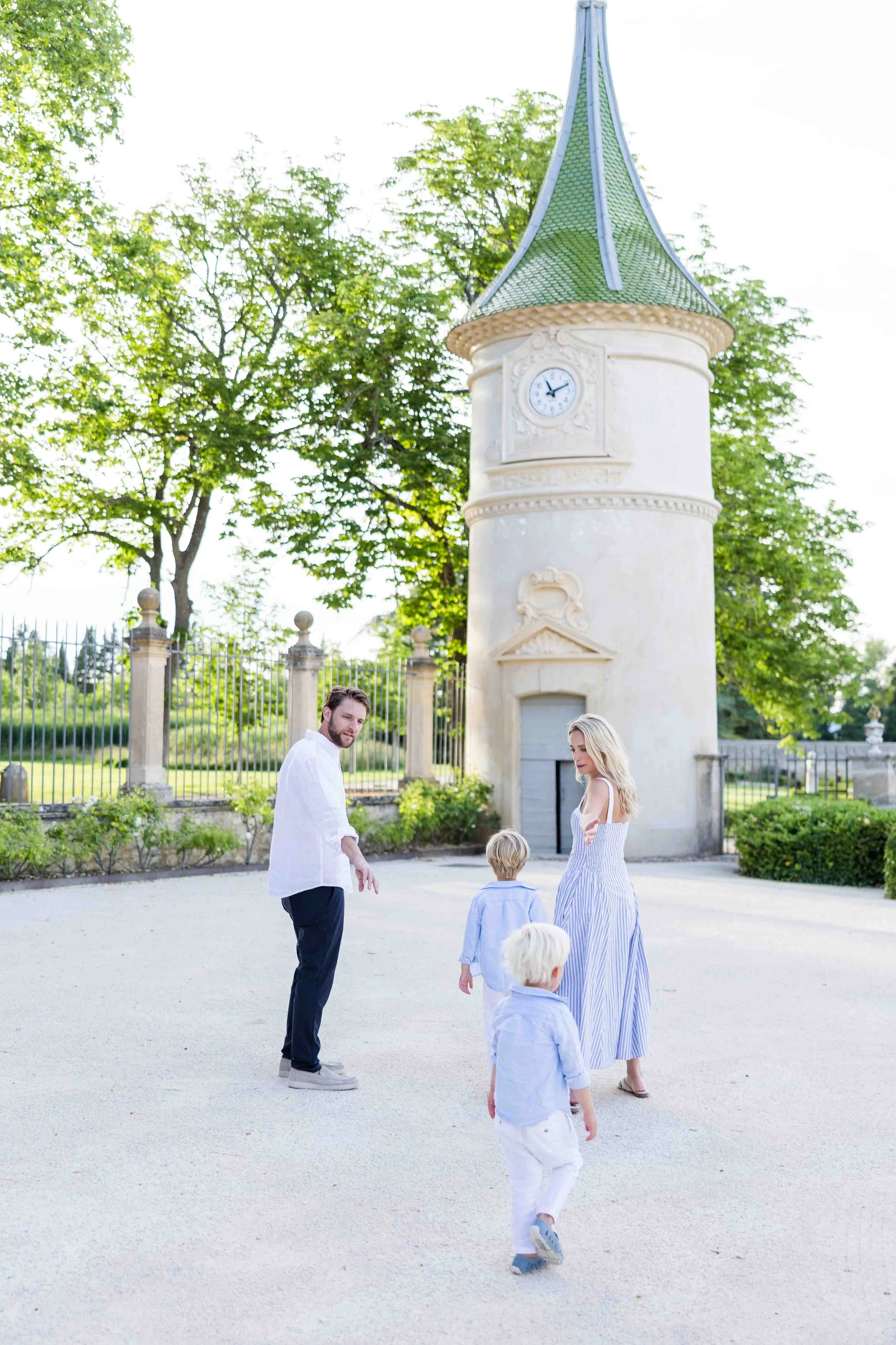 Family standing near a historic monument and fountain at Château de Fonscolombe, Provence.