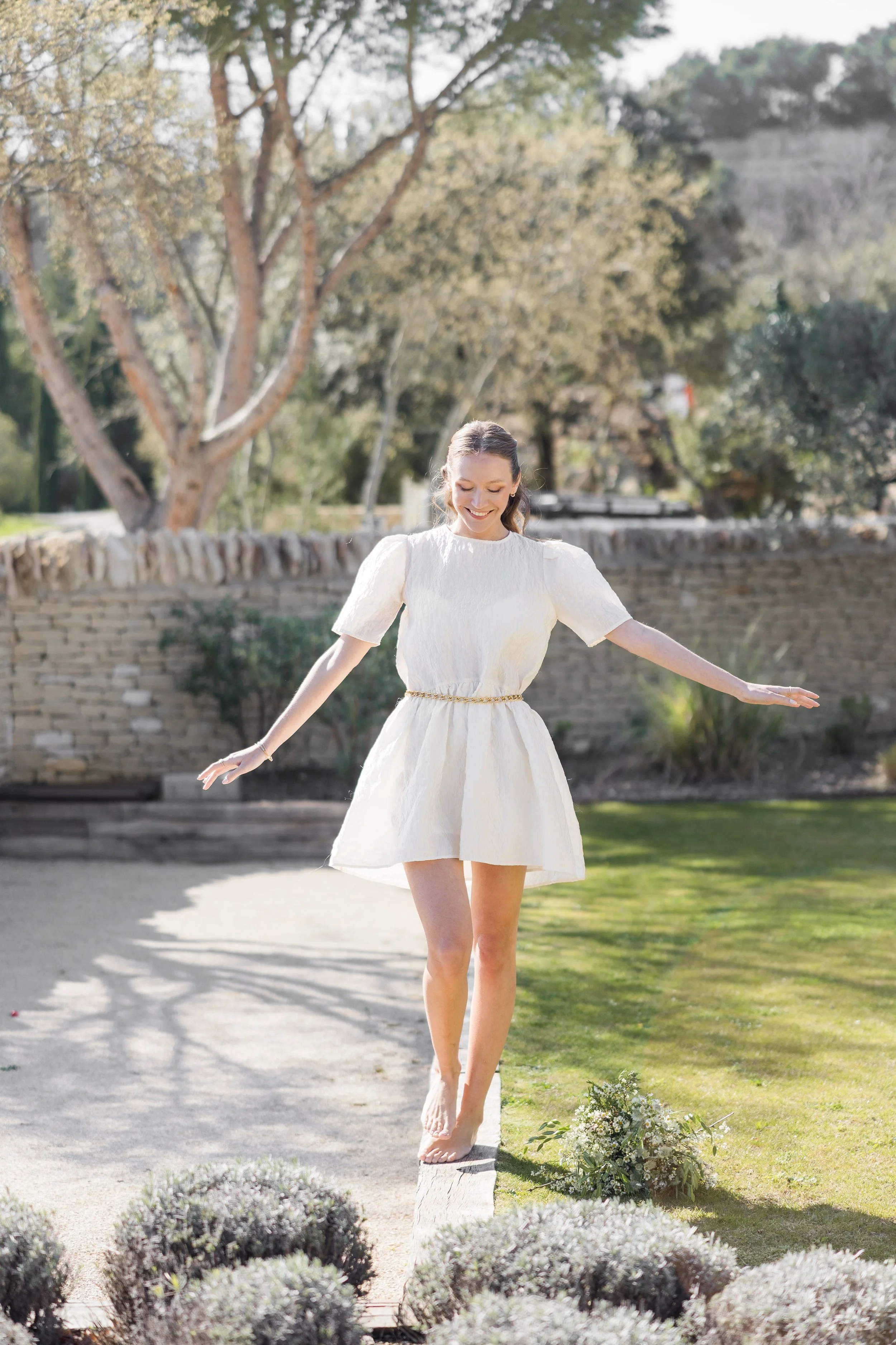 Woman in a flowy dress walking beside a pool in a stone villa in Gordes