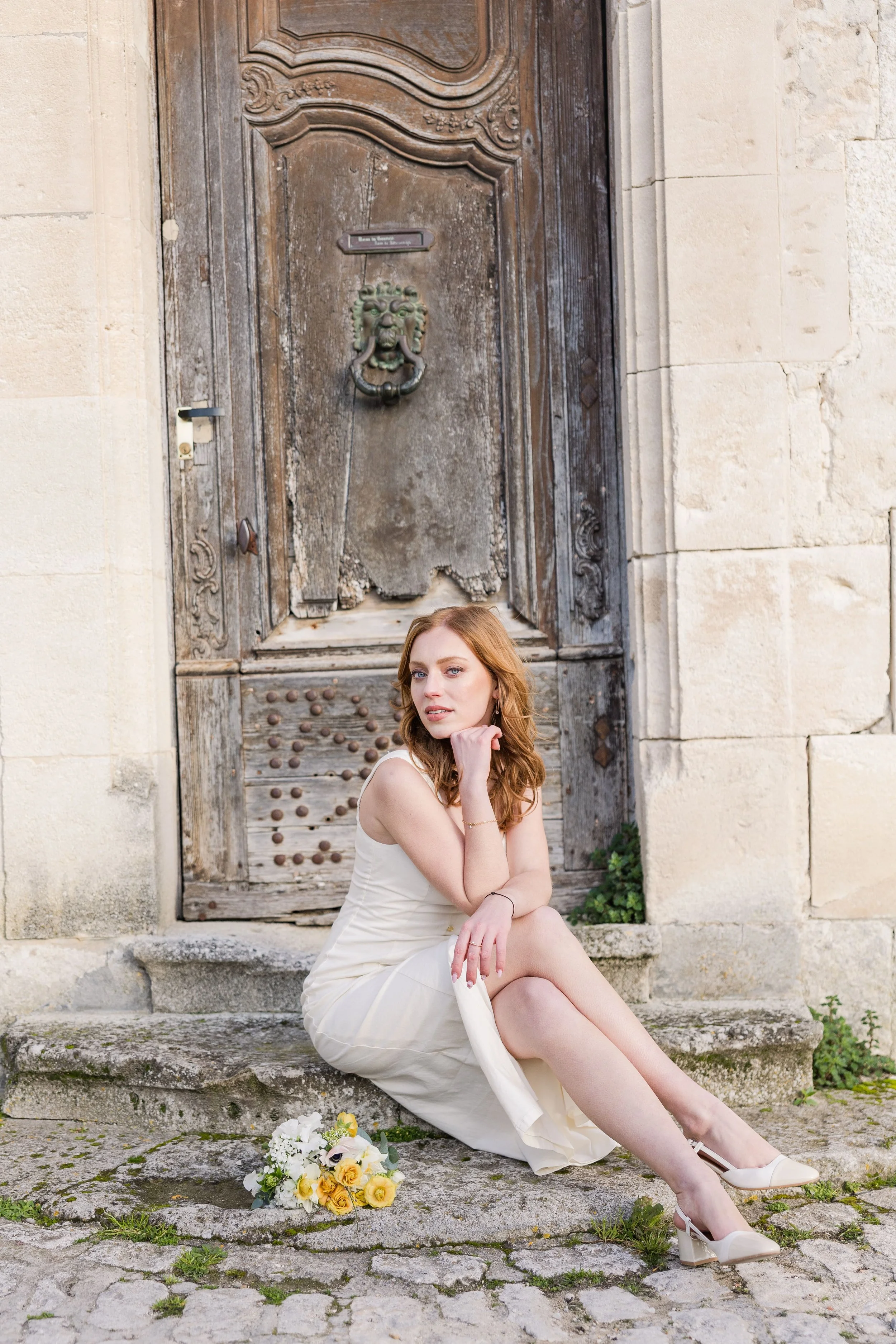 Woman with bouquet standing in a rustic stone alley in Provence