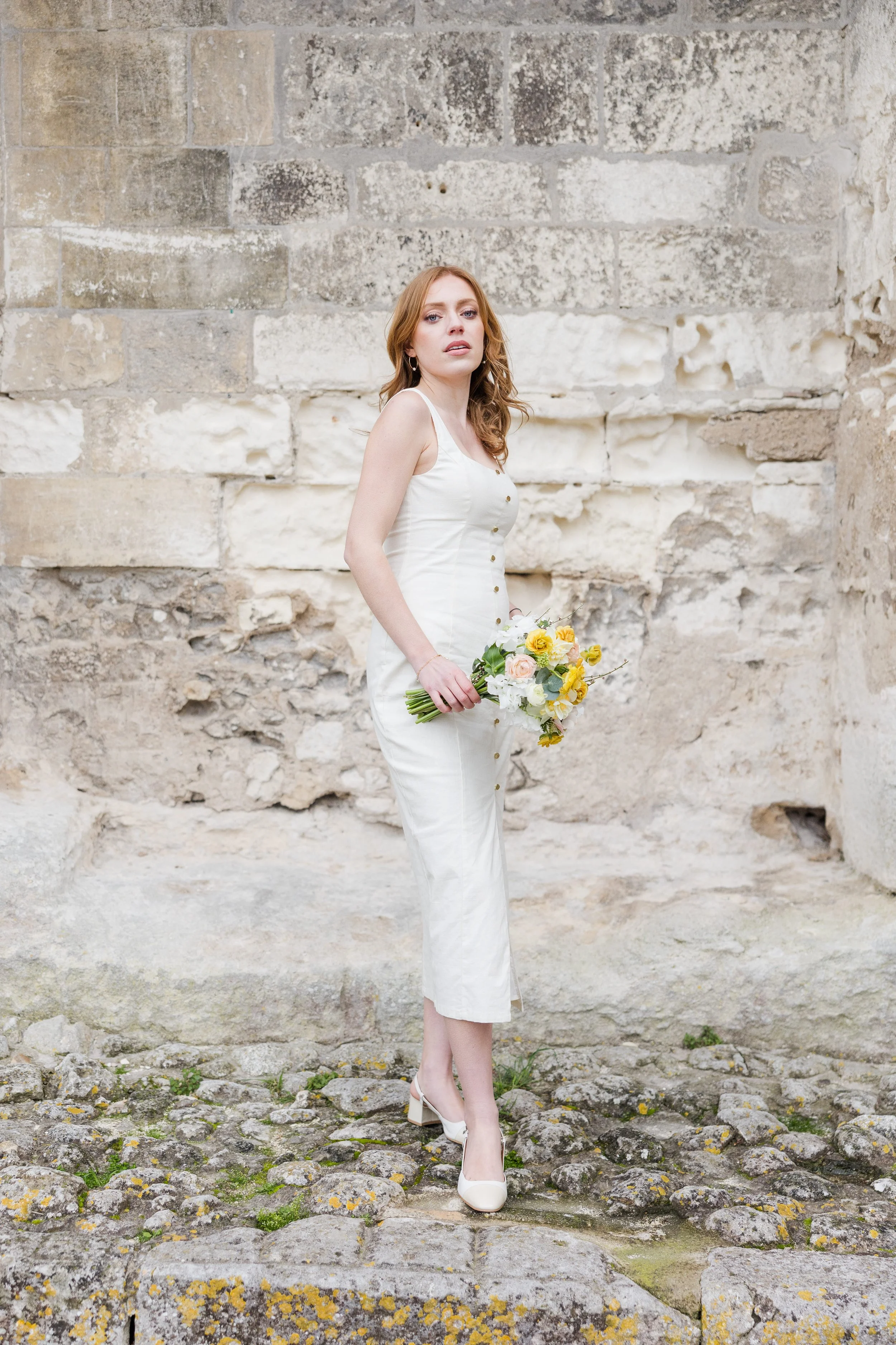 Woman walking with flowers in a stone street in Provence