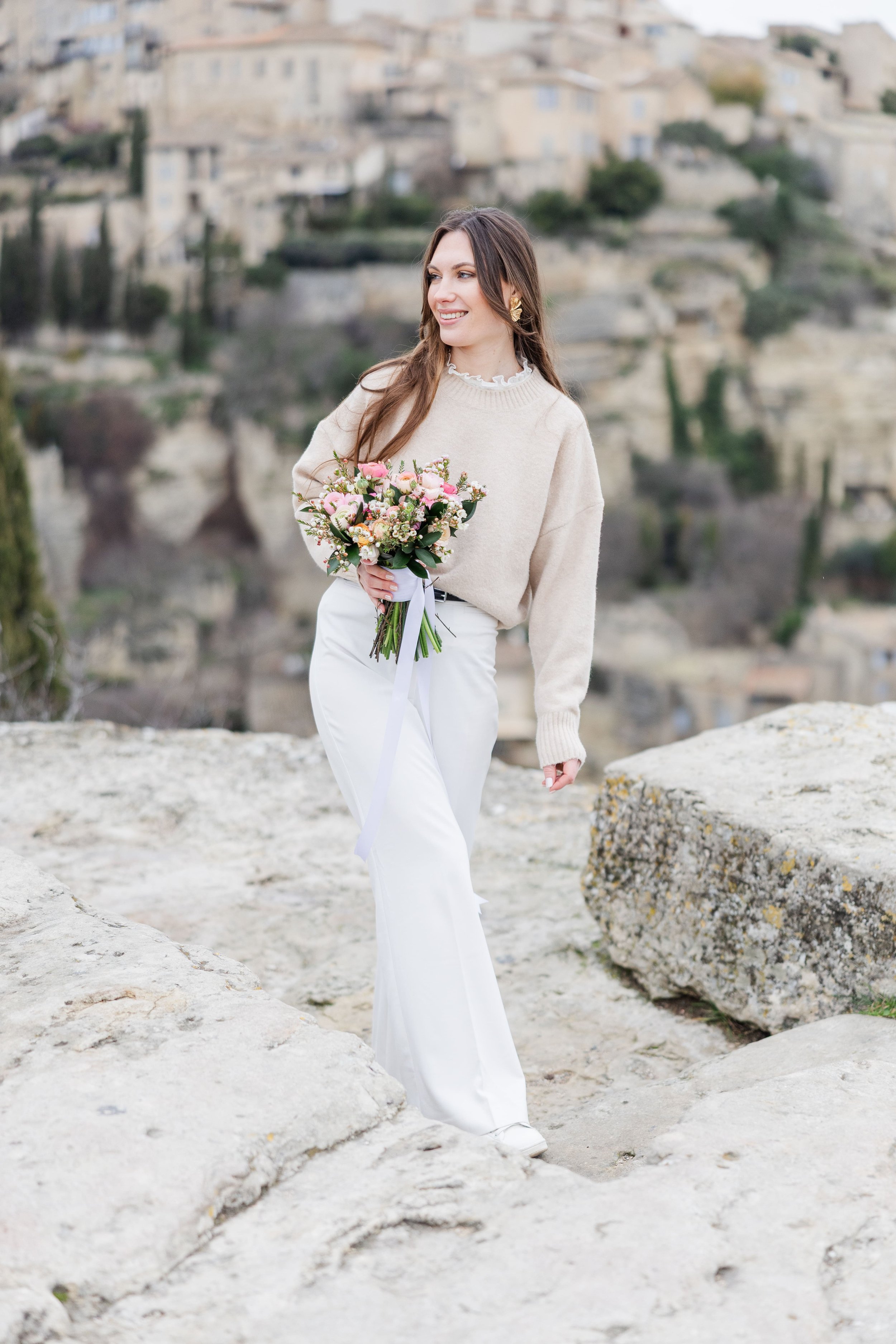 Elegant solo portrait of a woman in Gordes with vibrant pink flowers