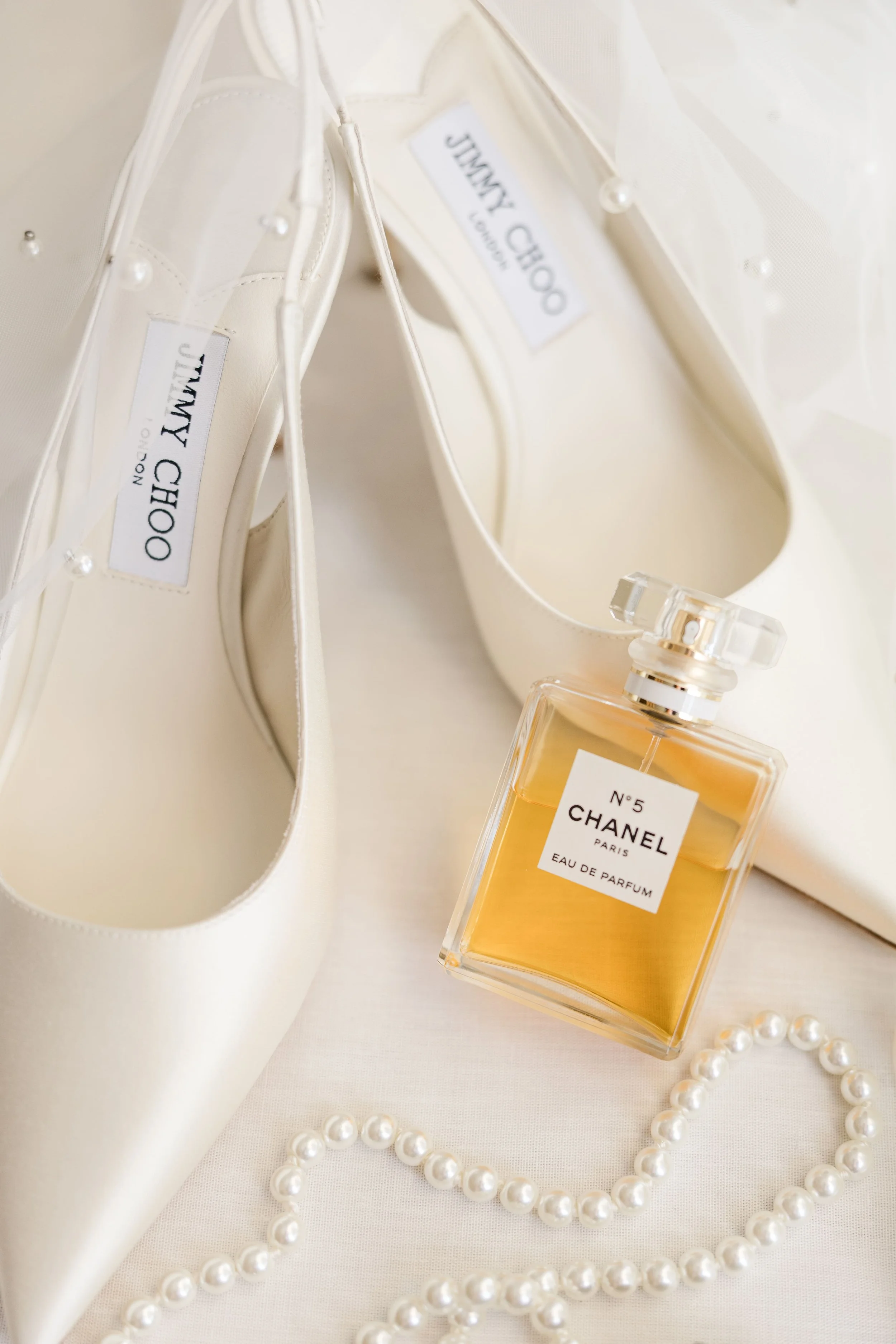 Luxury wedding flat lay featuring Jimmy Choo heels and Chanel No. 5 perfume