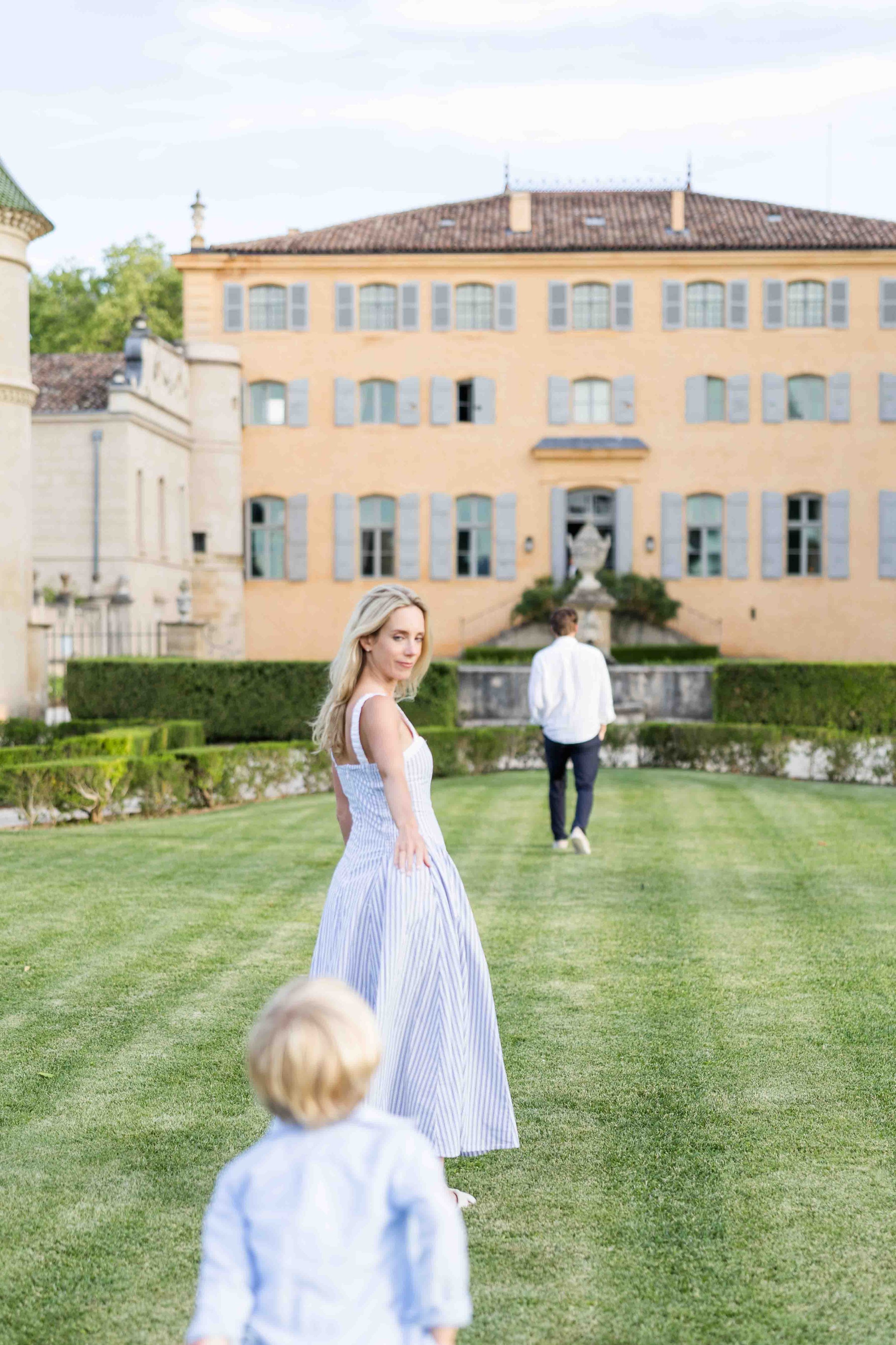 Family walking together across the manicured gardens of Château de Fonscolombe, Provence.