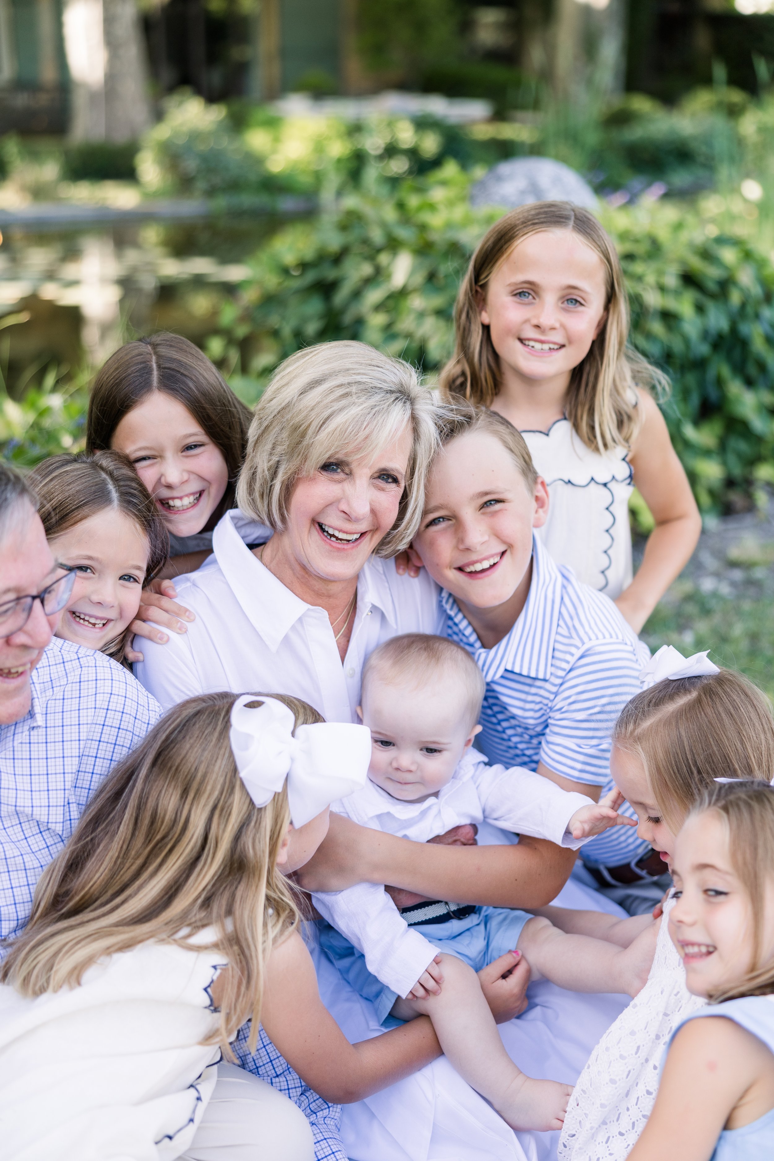 Grandma and grandpa hugging their grandkids smiling in casual family photo with Provence villa green garden background