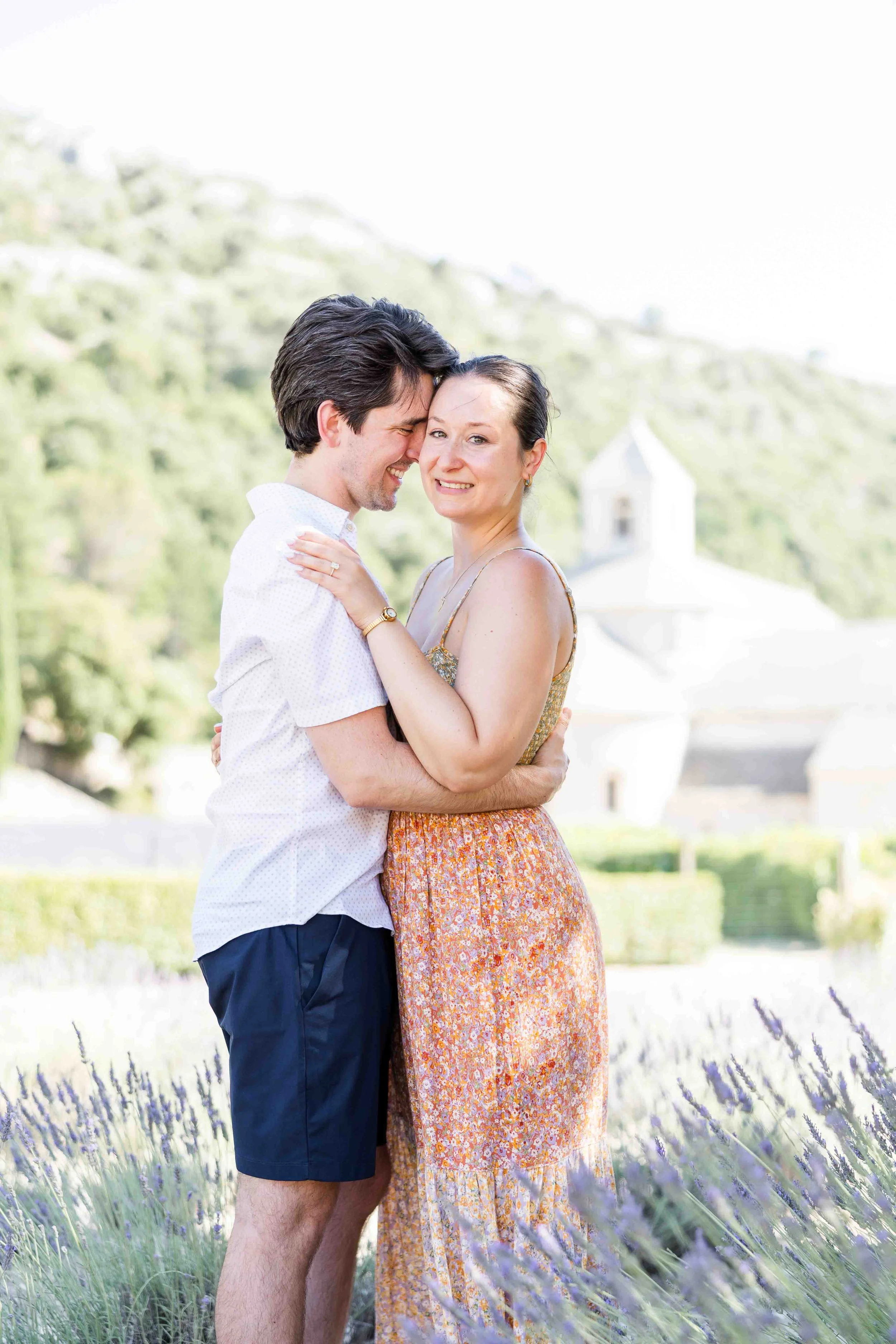 Couple embracing joyfully in front of Abbaye de Sénanque after their surprise proposal in Provence