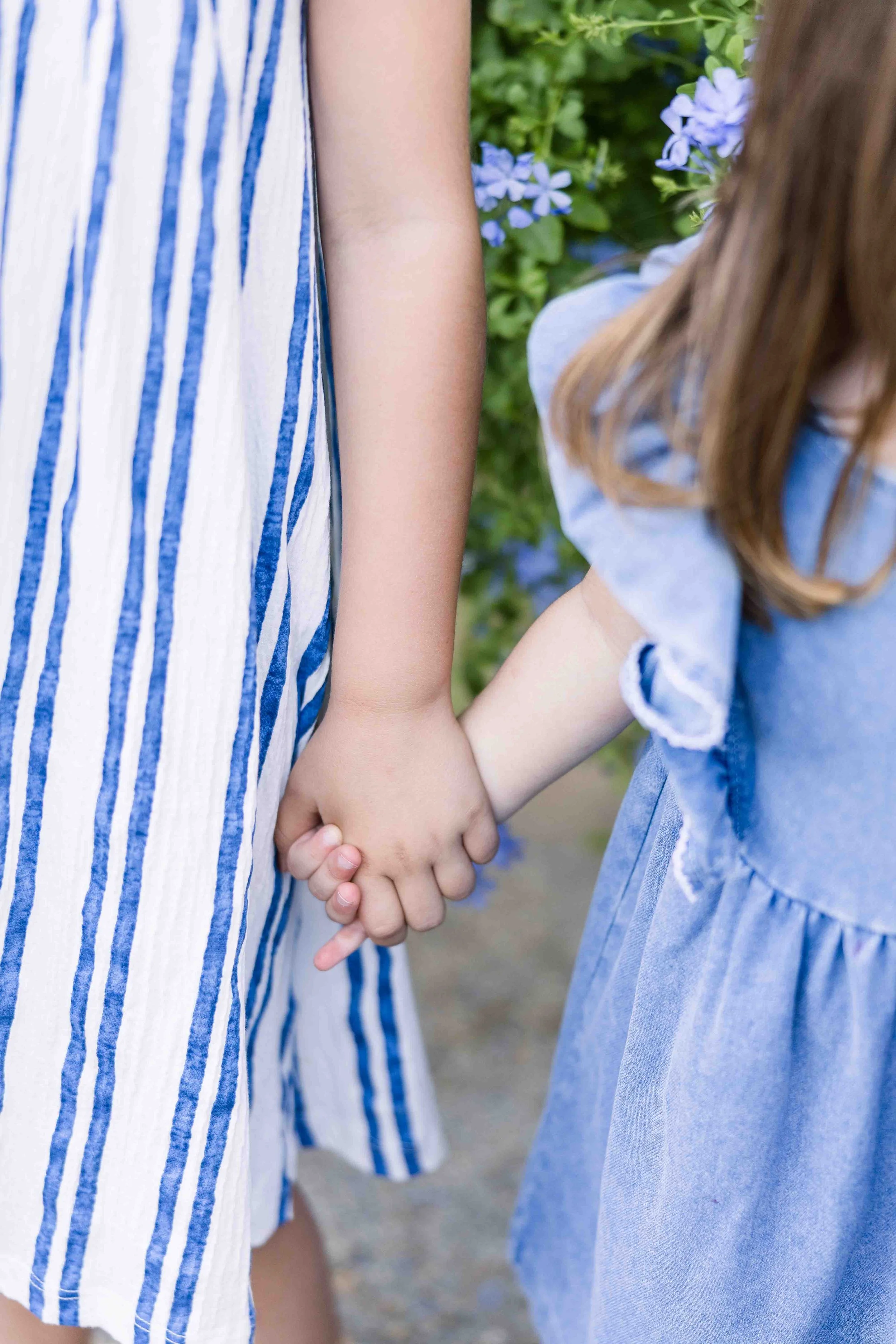 Close-up of two sisters holding hands during a family photo session in Provence.