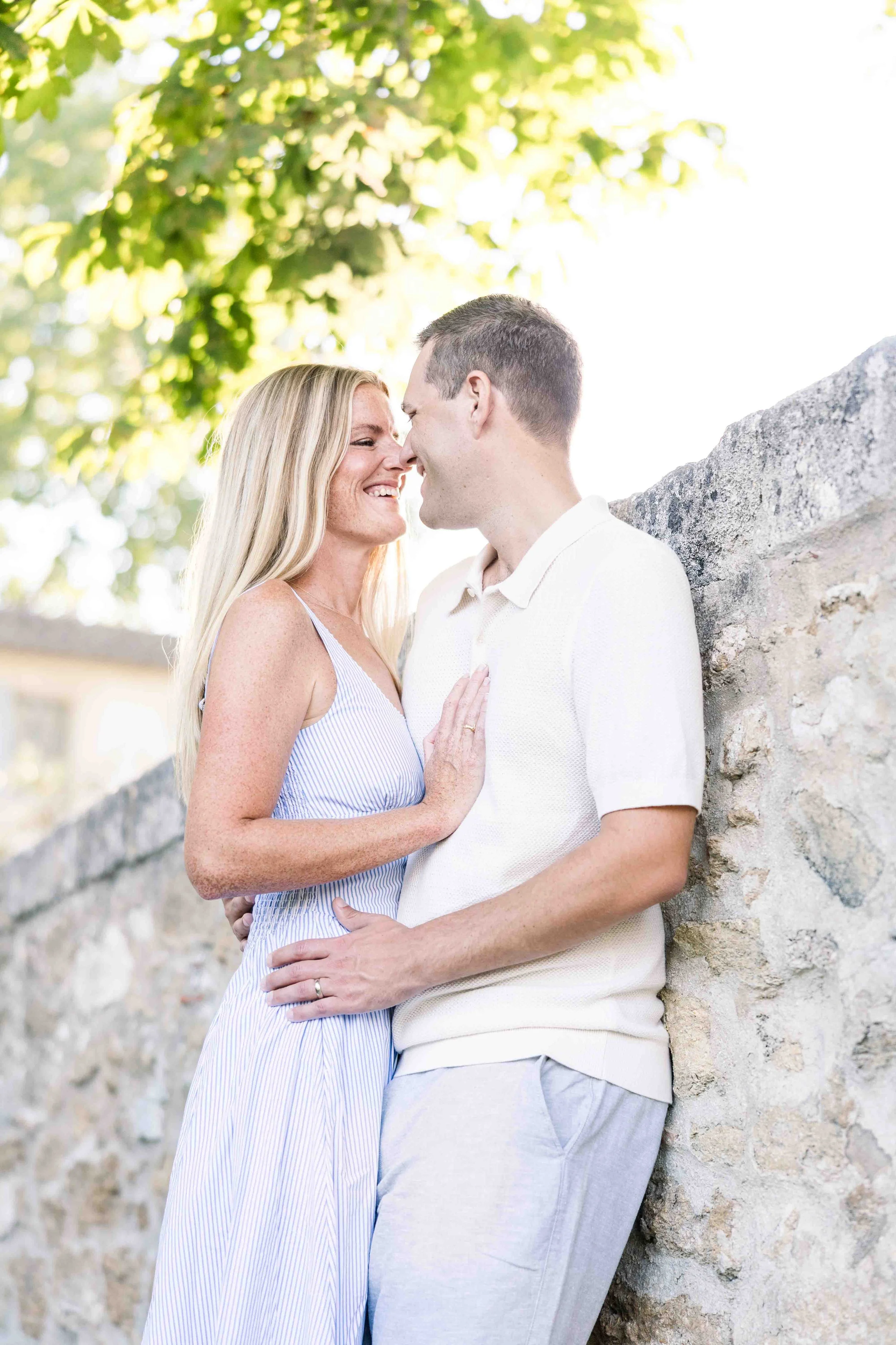 Couple sharing a tender embrace against a rustic stone wall at Domaine de Fontenille, celebrating 10 years together in Provence