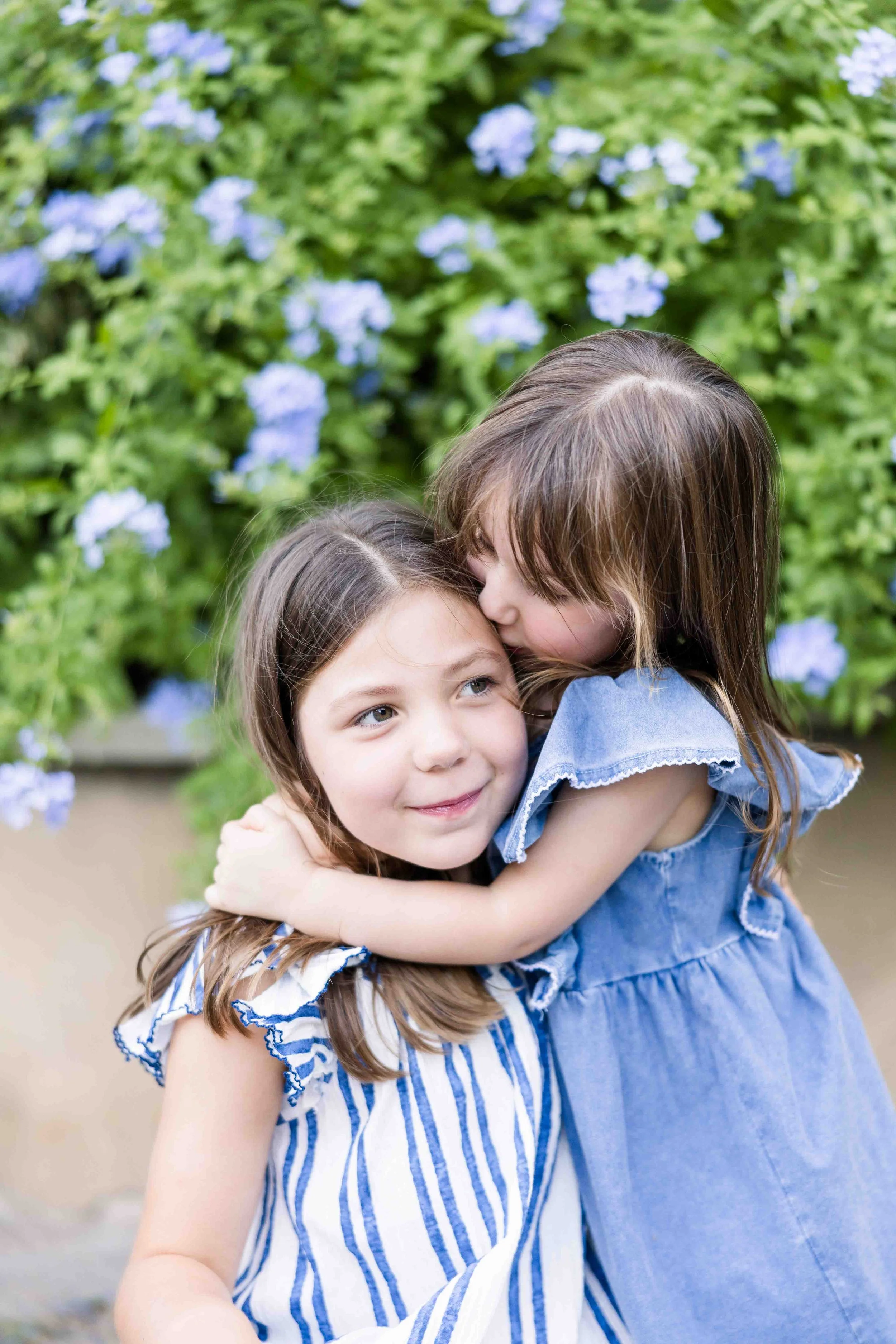 Two sisters standing in front of blooming flowers in a charming Provençal village.