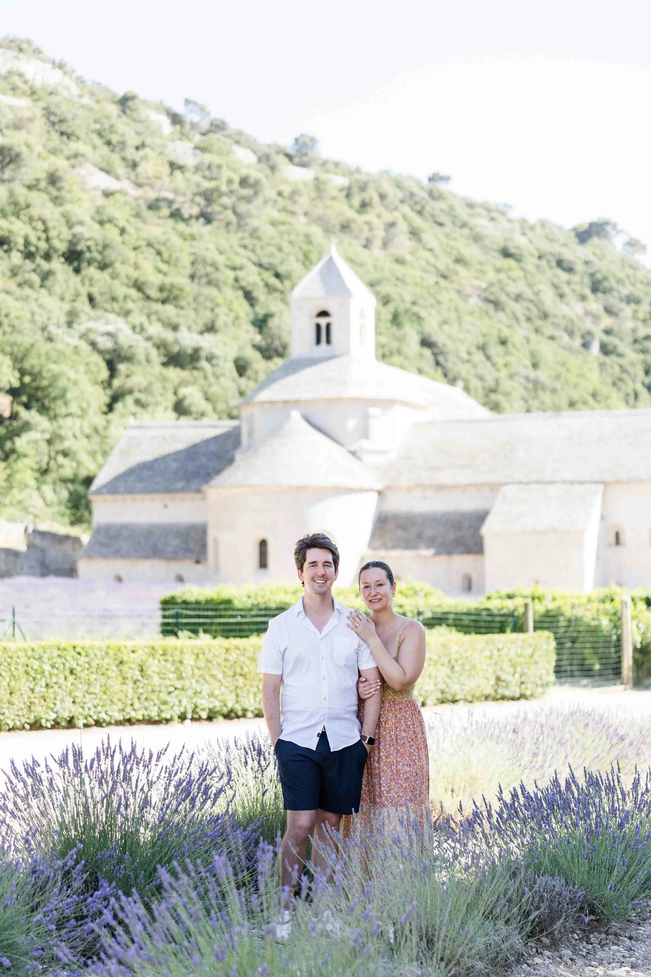 Couple standing in front of Abbaye de Sénanque surrounded by lavender fields during their proposal in Provence, France