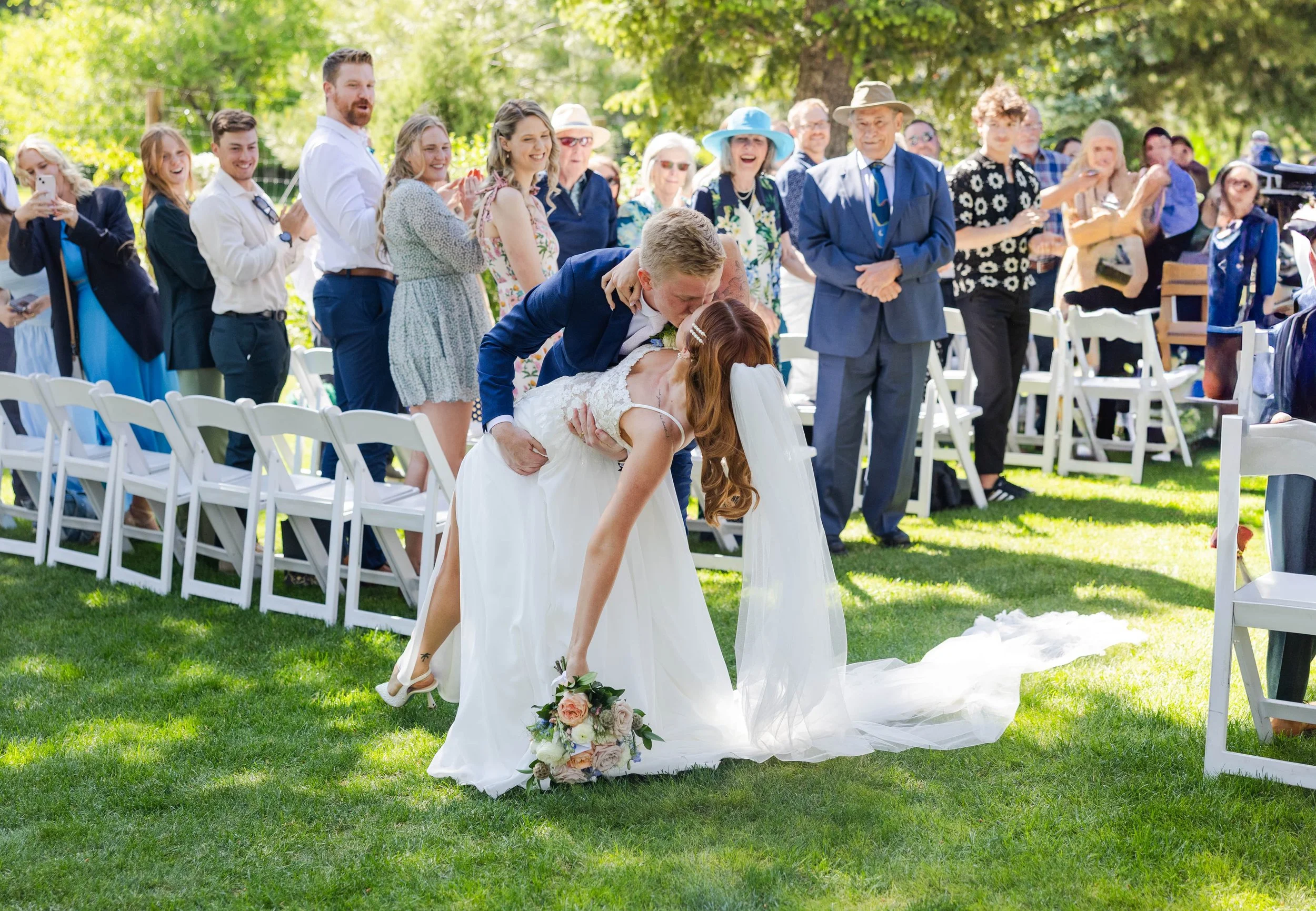Bride and groom sharing a romantic dip kiss during the wedding ceremony.