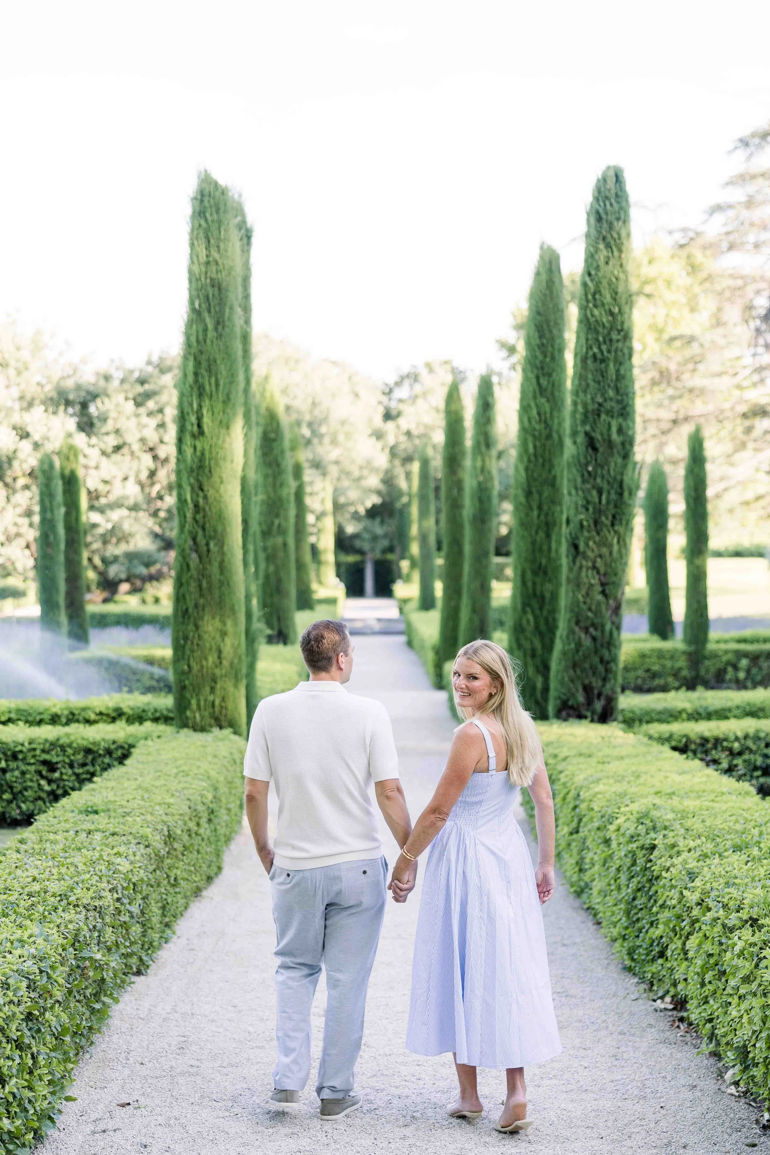 American couple celebrating their 10 year anniversary walking down a cypress-lined path at Domaine de Fontenille, Lauris, Provence