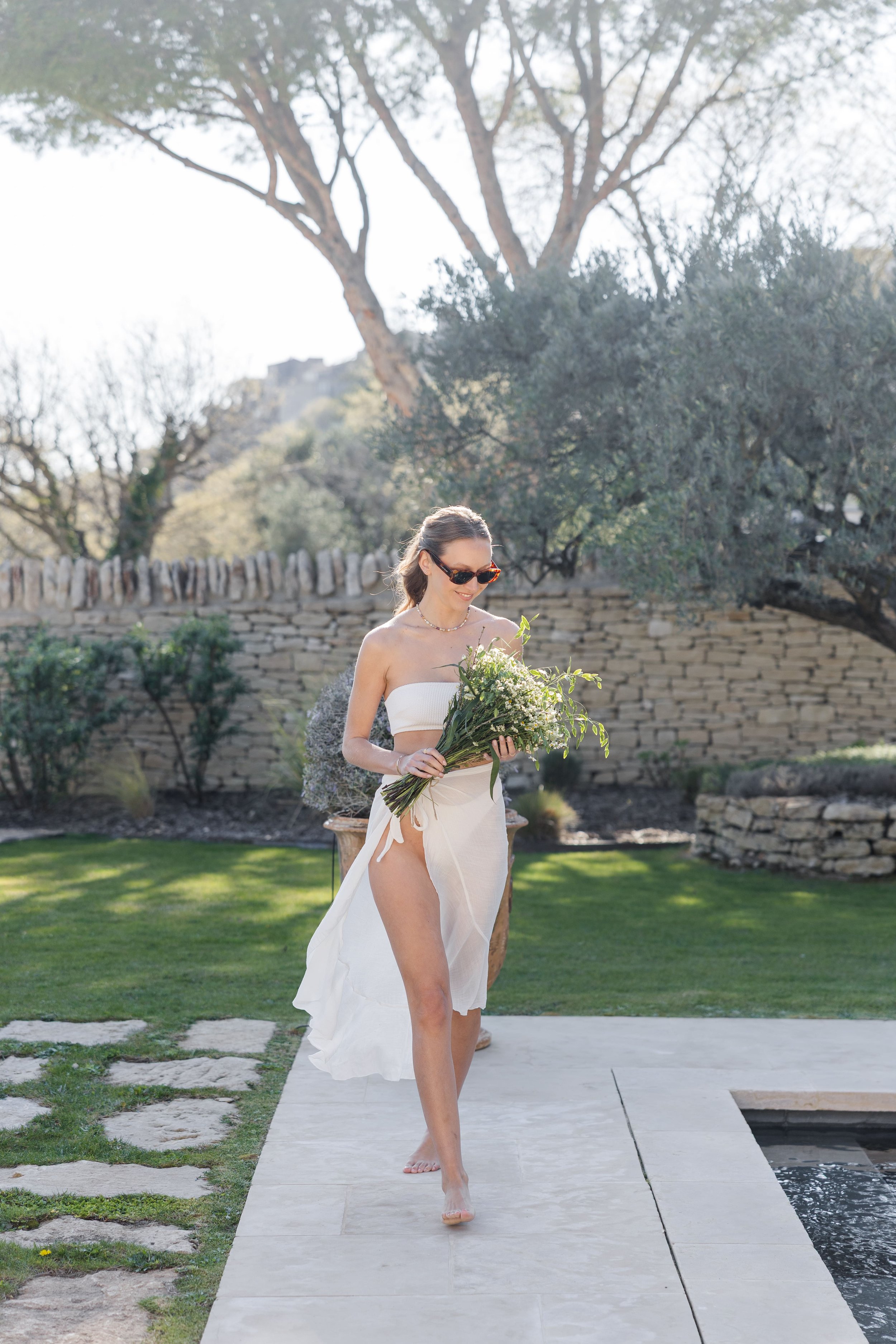 Woman walking by the pool in a lush garden of a luxury villa in Gordes, Provence