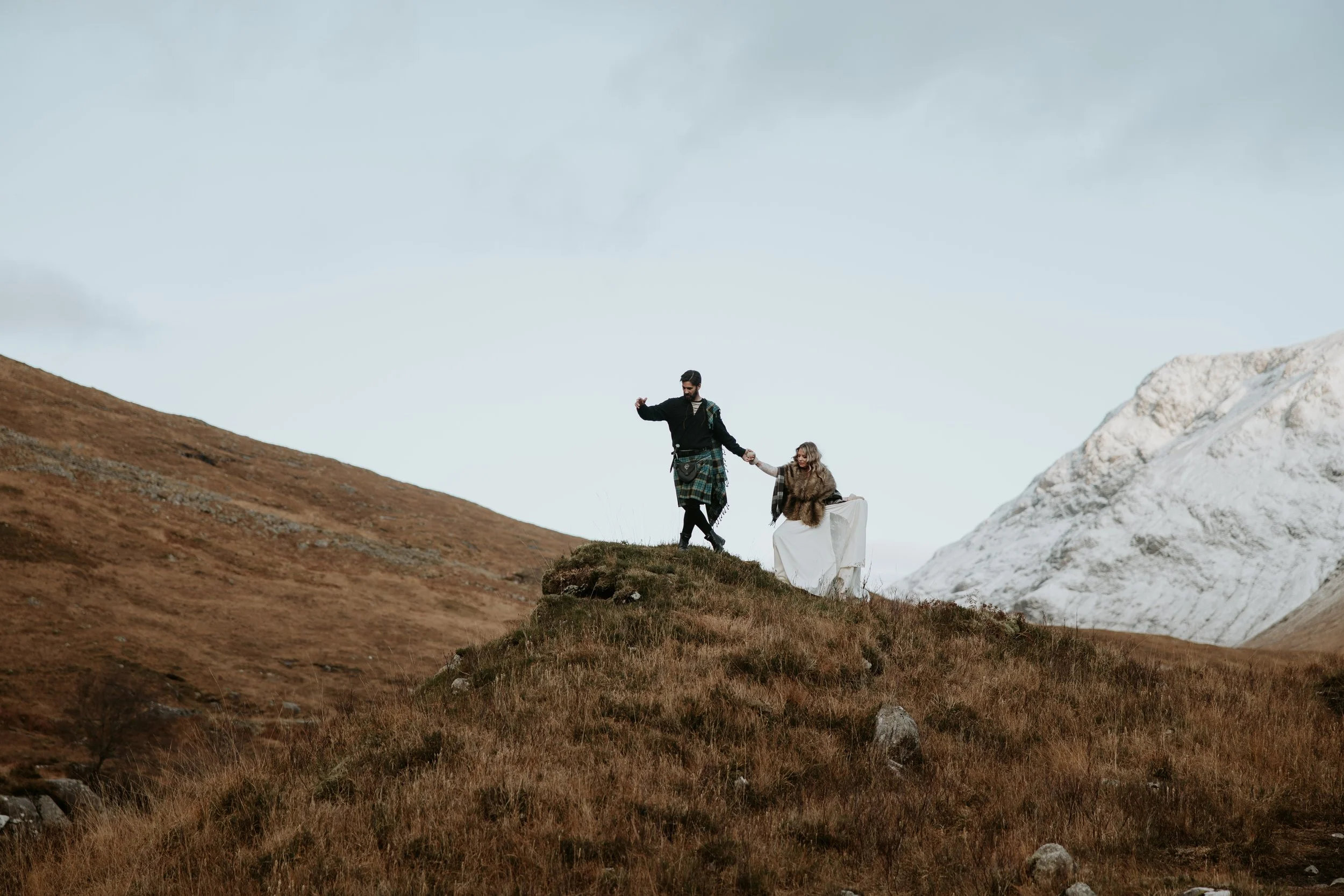 Couple walking over hills during Glencoe Scotland Elopement