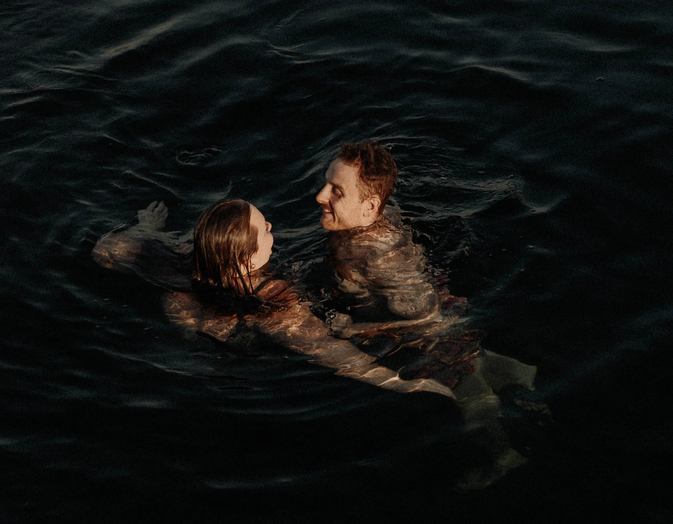 Man and woman swimming at the beach during sunset at Lake Washington in Seattle, couple is swimming in the water for their photoshoot