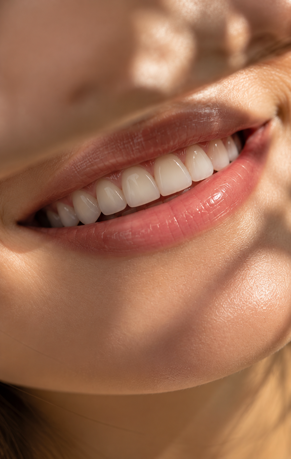 Close-up of a smiling person's mouth showing white teeth and pink lips.
