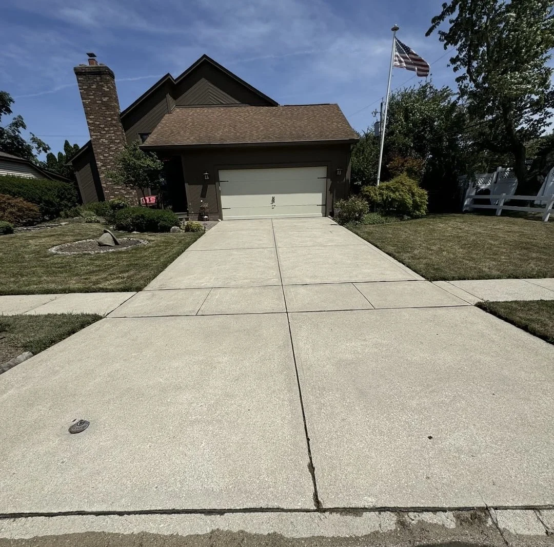 Front view of a house with a concrete driveway that has just been pressure washed.