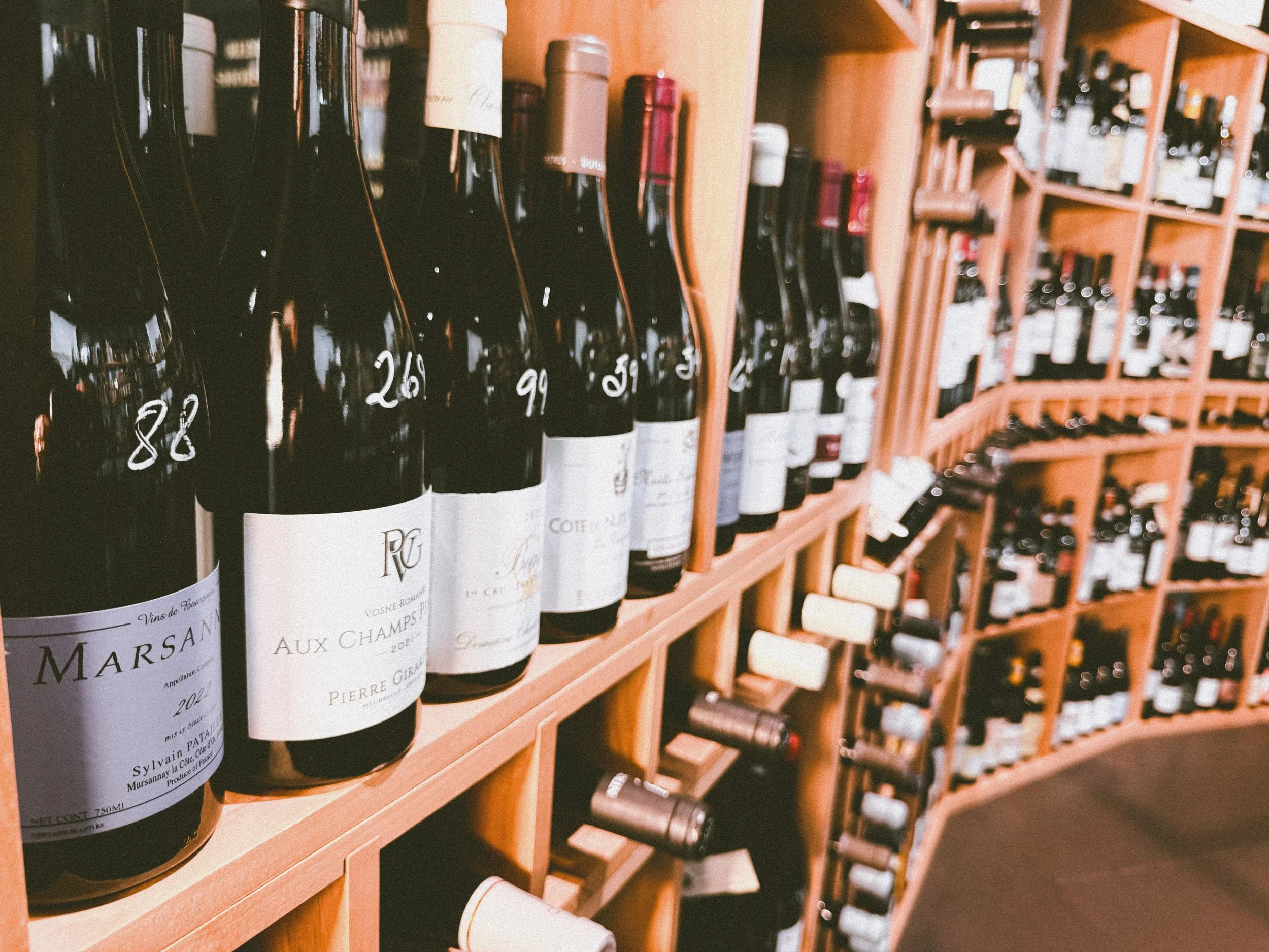 Wine bottles displayed on wooden shelves in a wine shop.