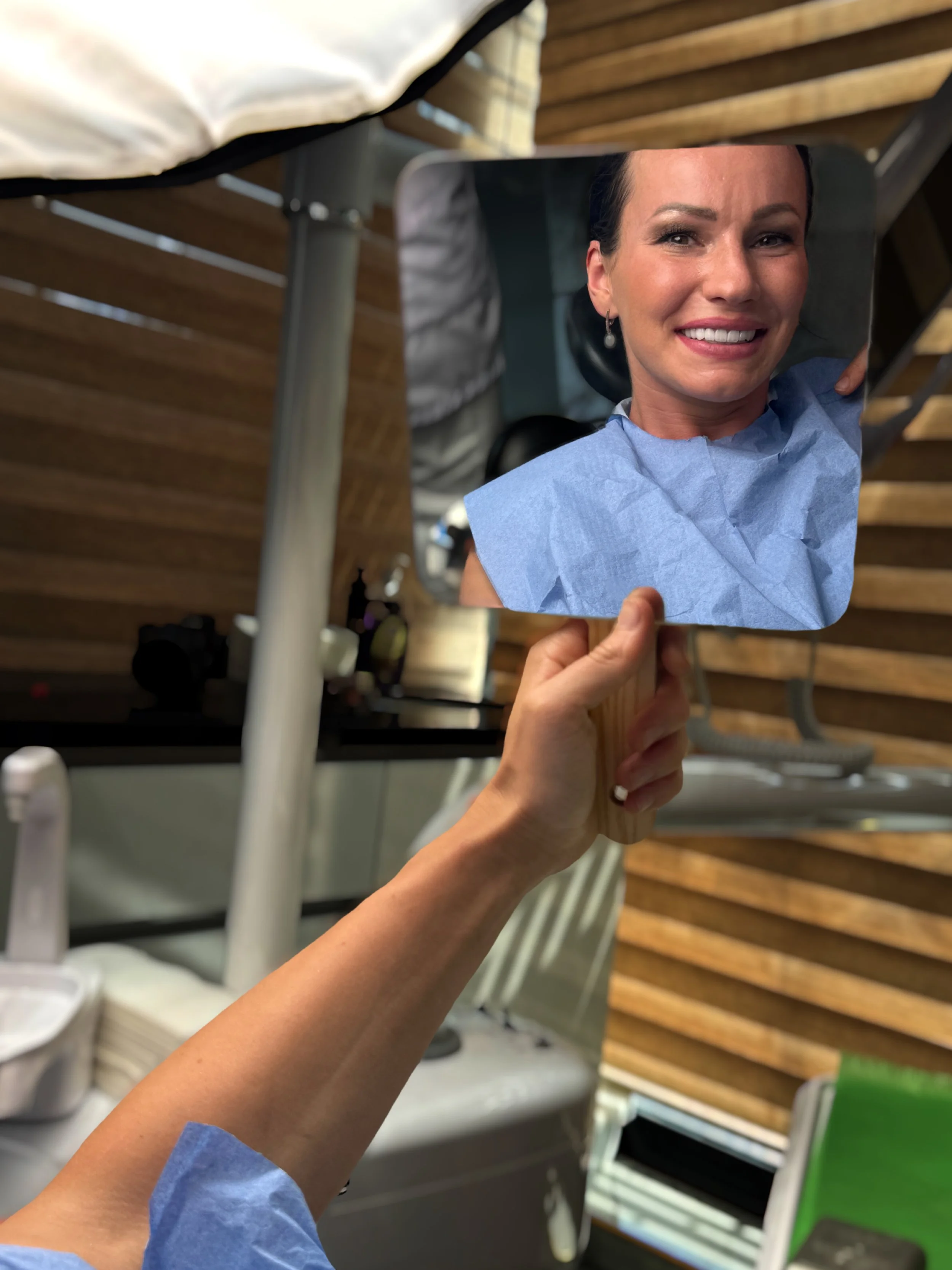 Henkilö katsoo peiliin, jonka he pitää kädessään, ja näkee hymysuin kasvonpeilin kautta, mikä näkyy kuvassa.