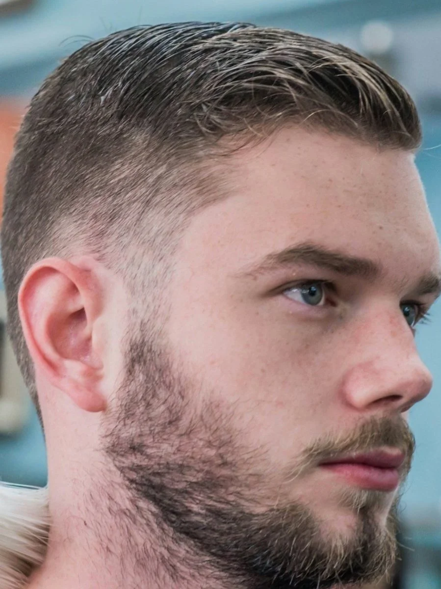 Nuoren miehen profiilikuva, jossa on lyhyt, siisti leikkaus, ja parrakas alaosa.