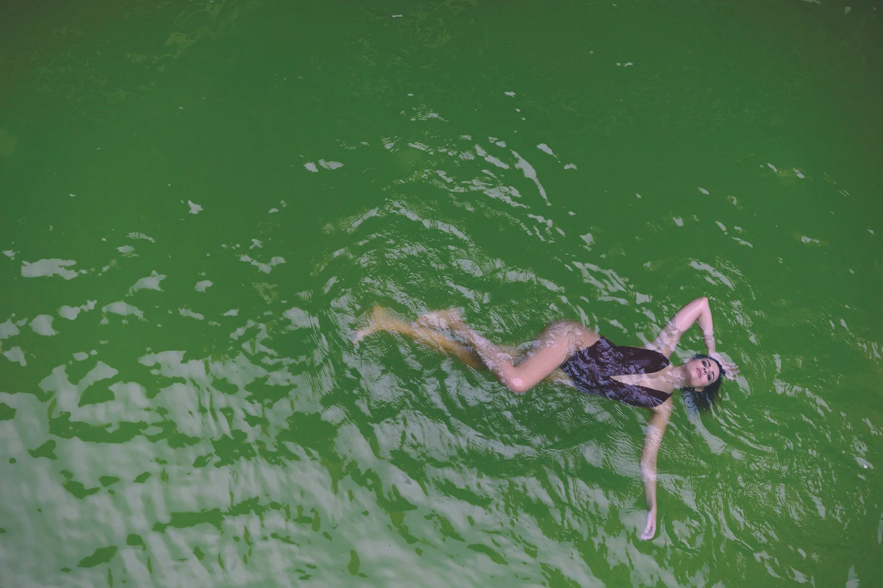 Nainen makaamassa applauduksissa vihreässä vedessä.