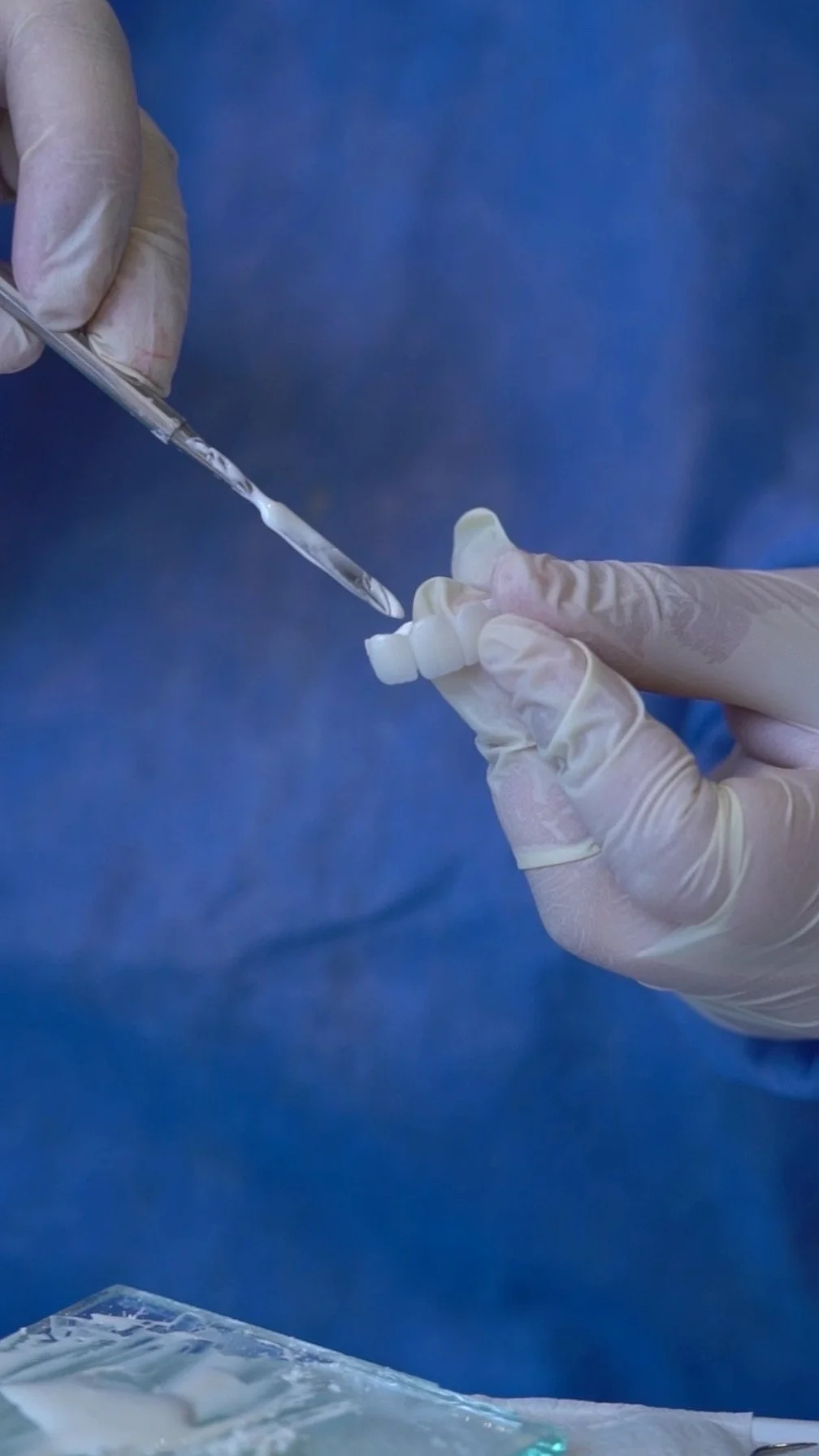 Lääkäri tai hammaslääkäri käsittelee hammasproteesia tai hammasimplanttia käyttäen sterilisiä käsineitä ja työkaluja.