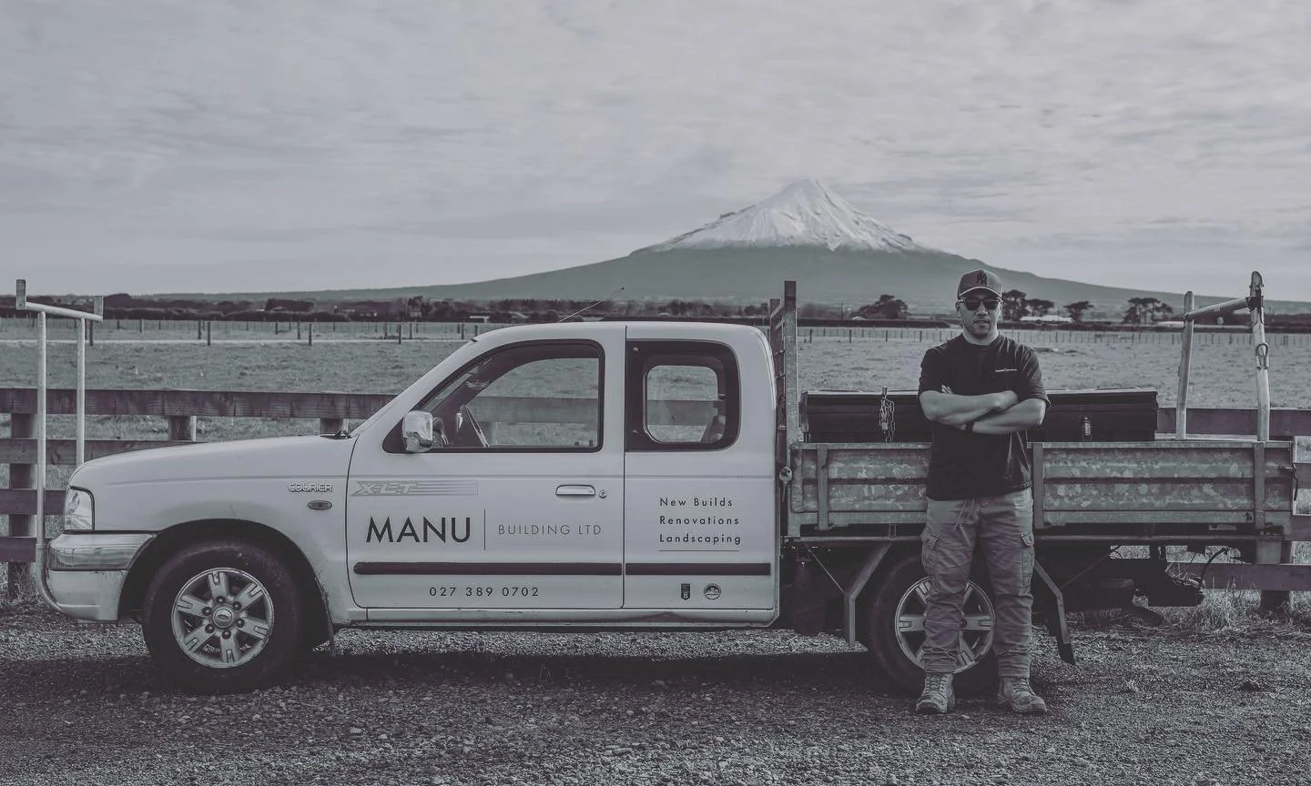 Man standing next to a pickup truck with a mountain in the background.
