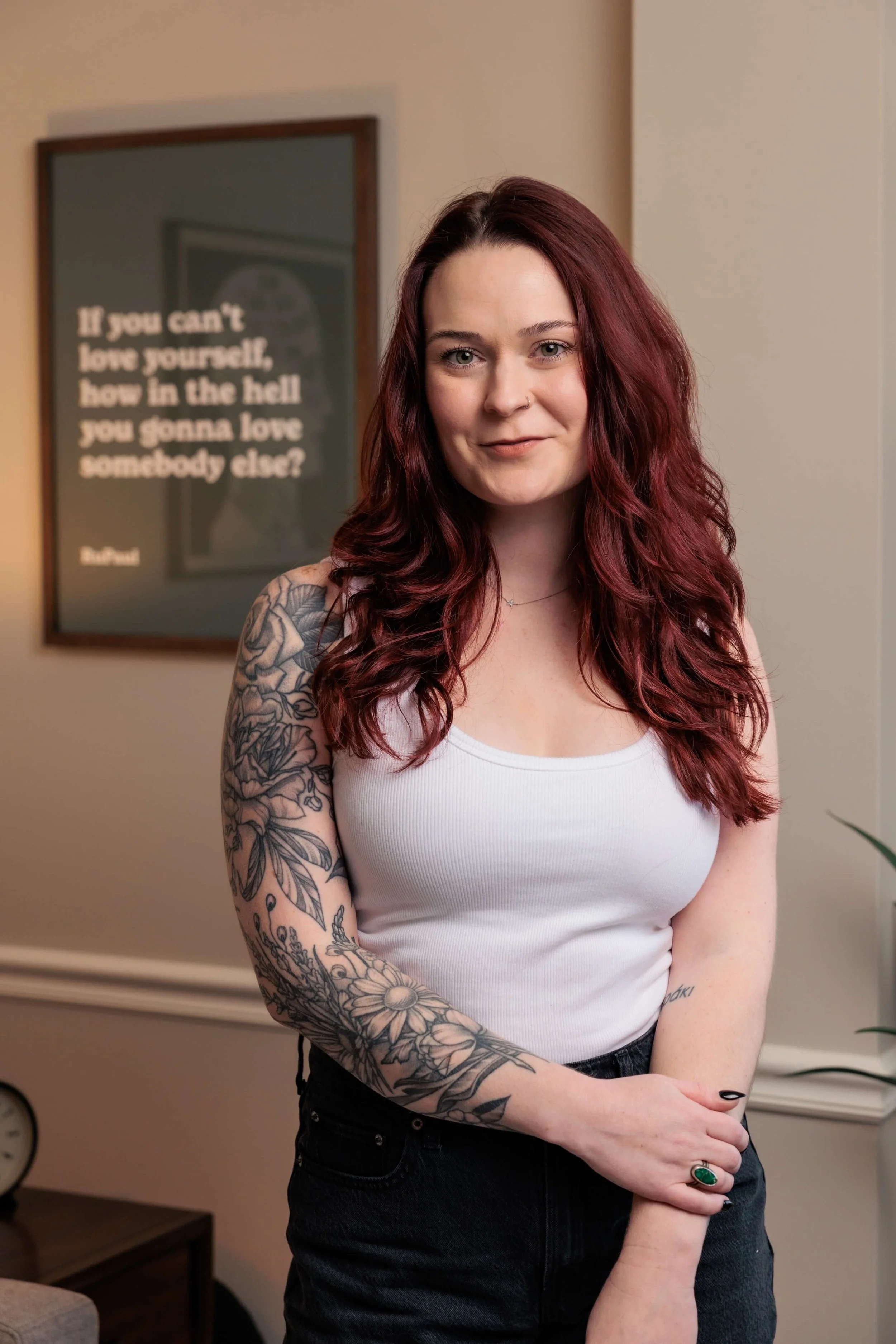 Kaylie stands in a white tank top, clutching one wrist.