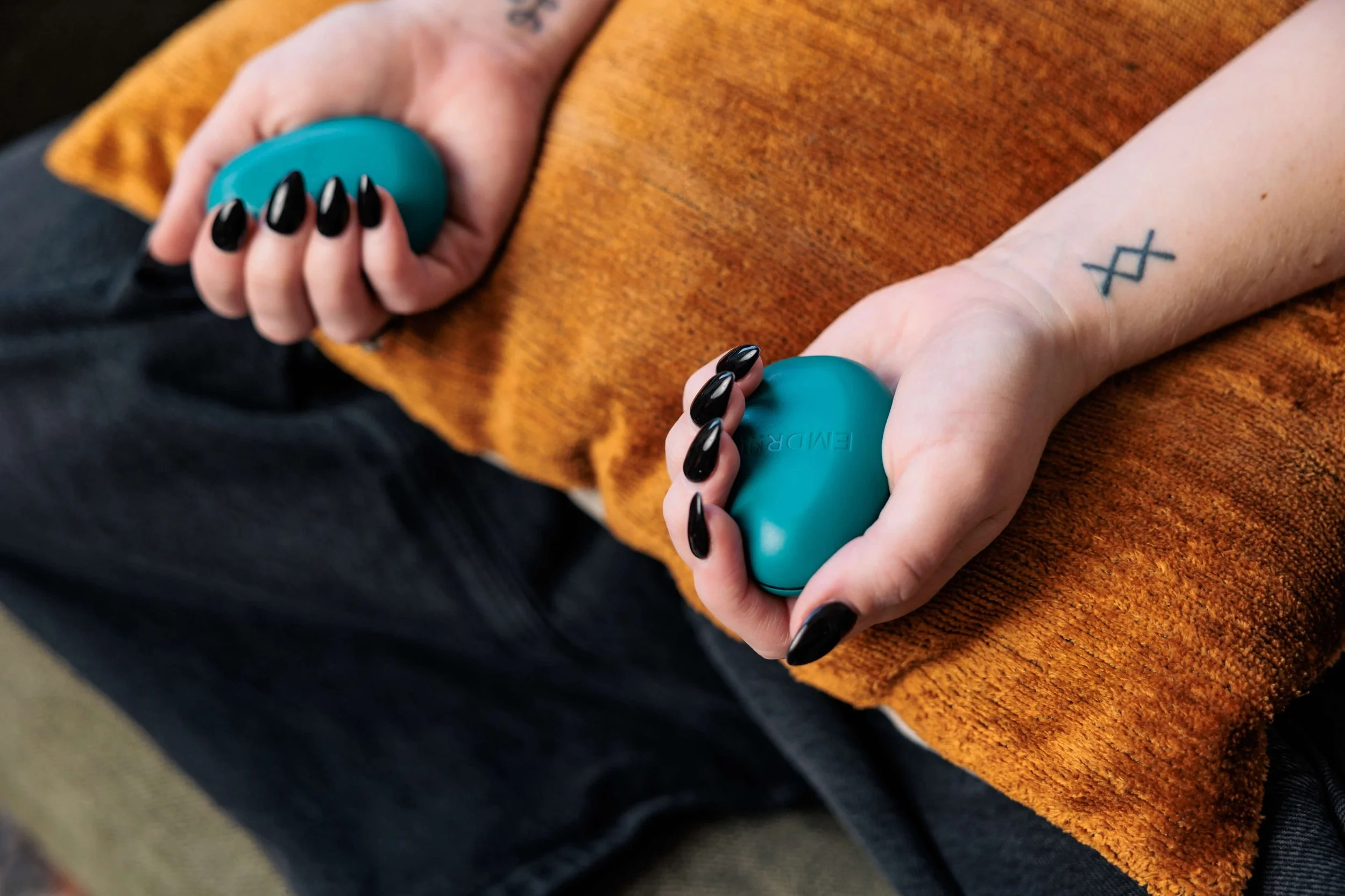 Kaylie folds blue EMDR buzzers over a yellow pillow.