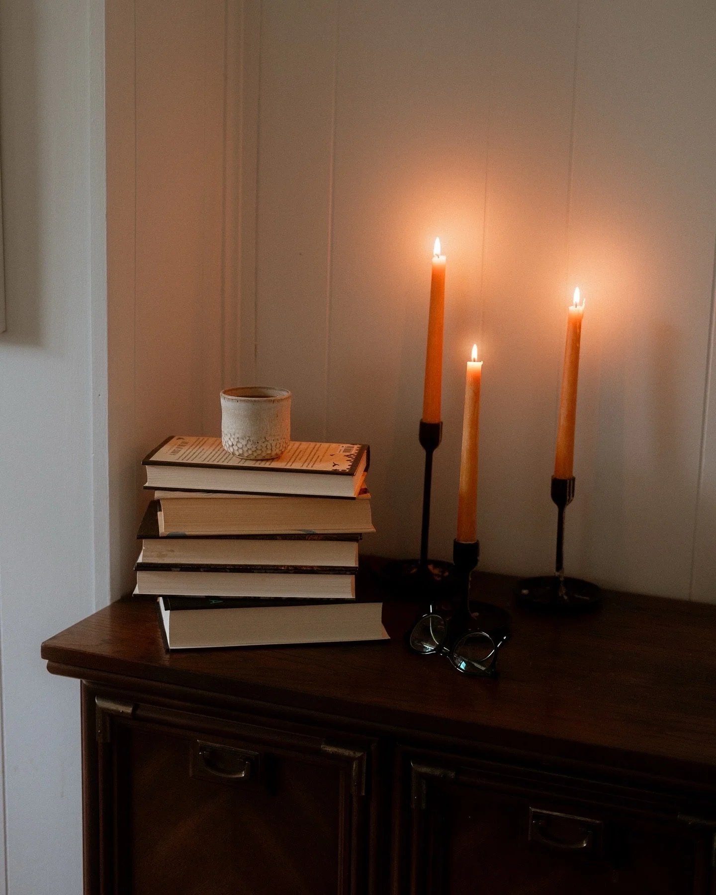 Stack books beside burning orange candles.