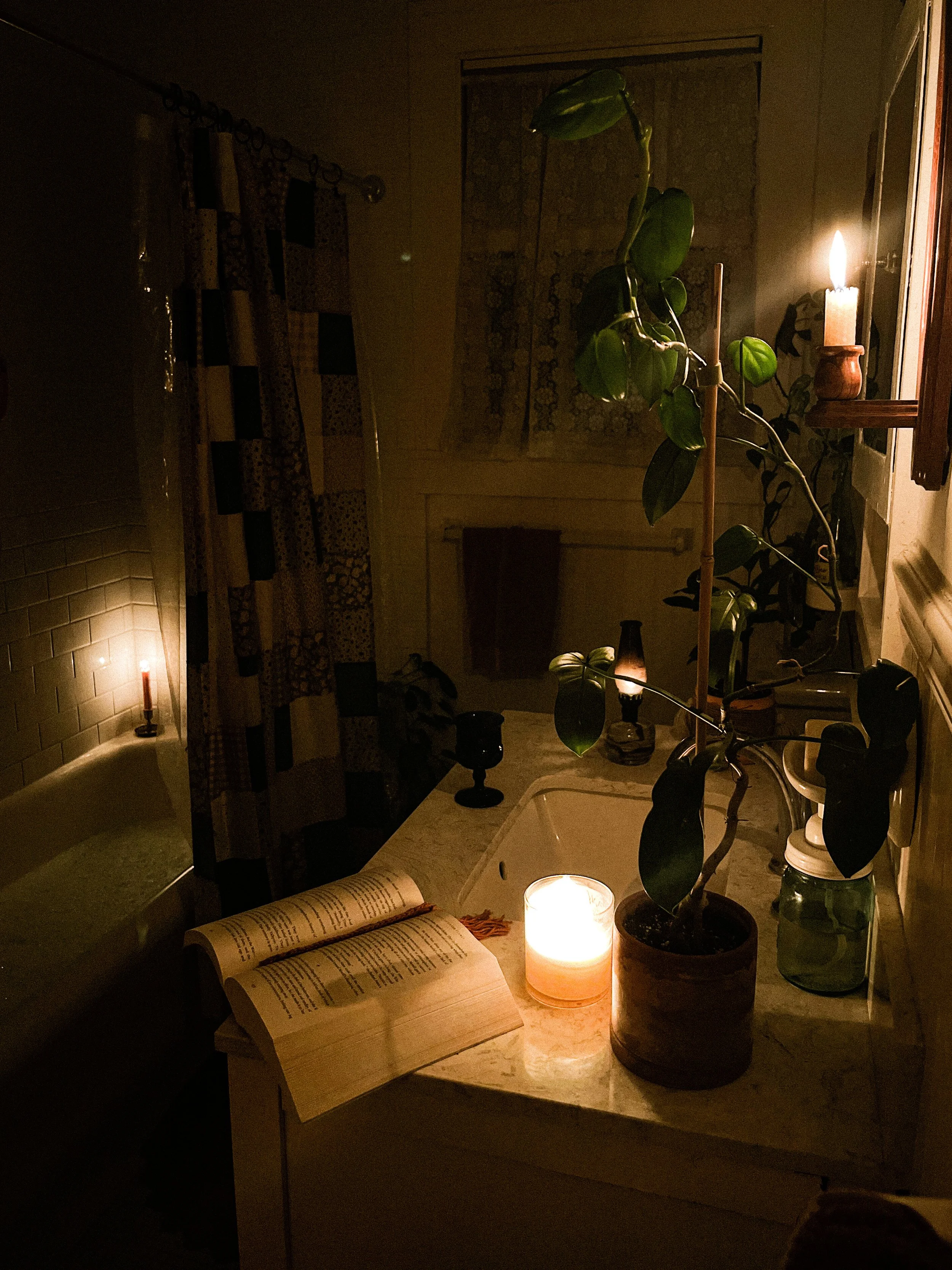 Candelit bathroom with a book open on the container
