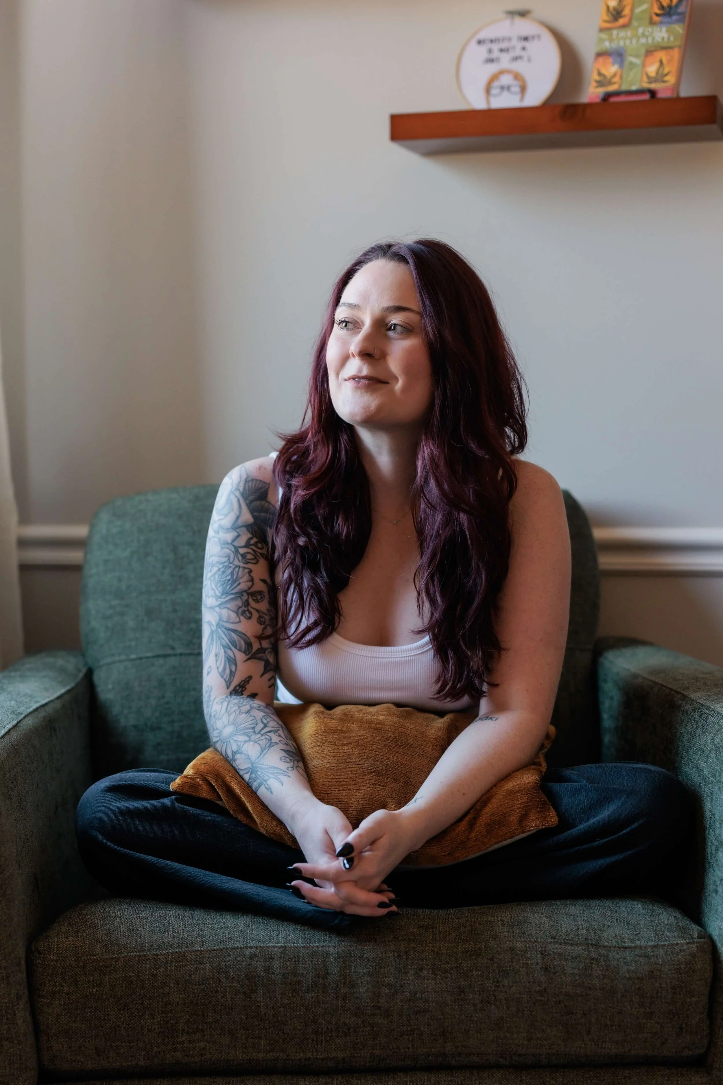 Kaylie sits in an armchair, curled up with a pillow.