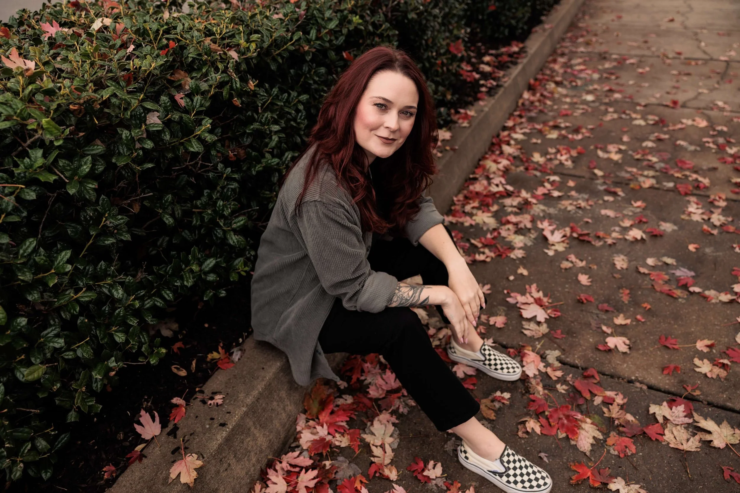 Kaylie sits outside, surrounded by red fallen leaves.