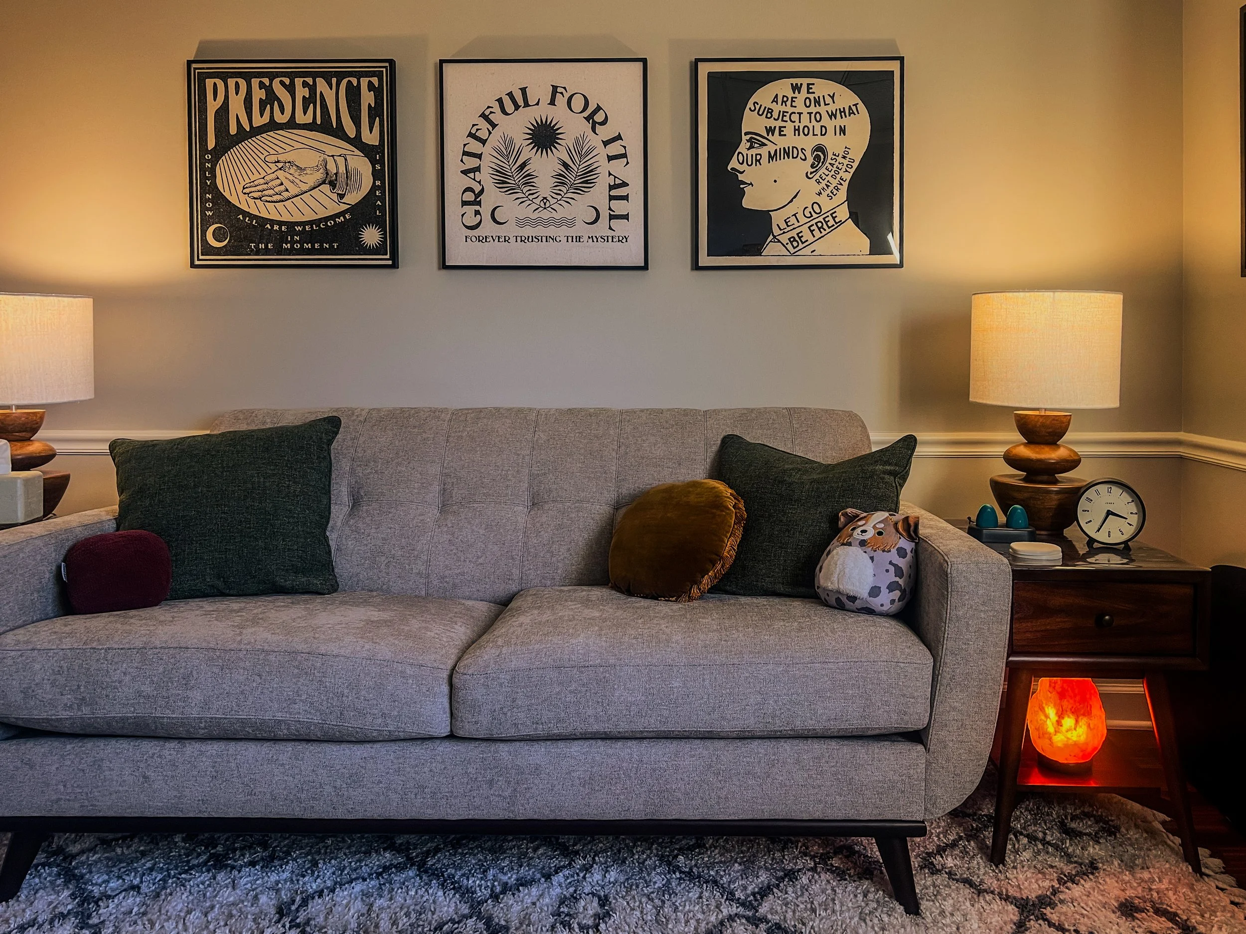 Interior of a therapy office with a gray coach and witchy wall art.