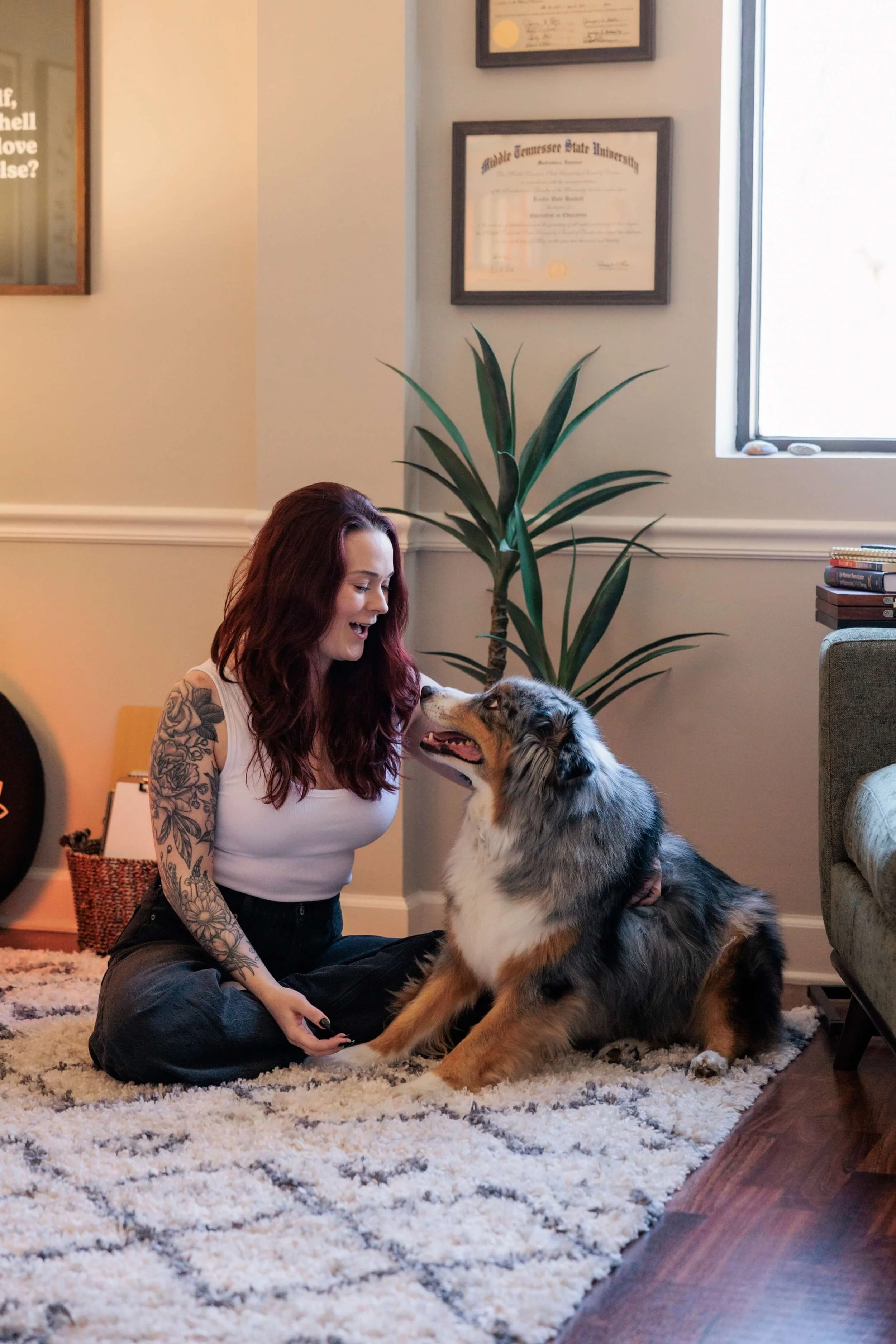 Kaylie sits on the floor with her Australian Shepherd.