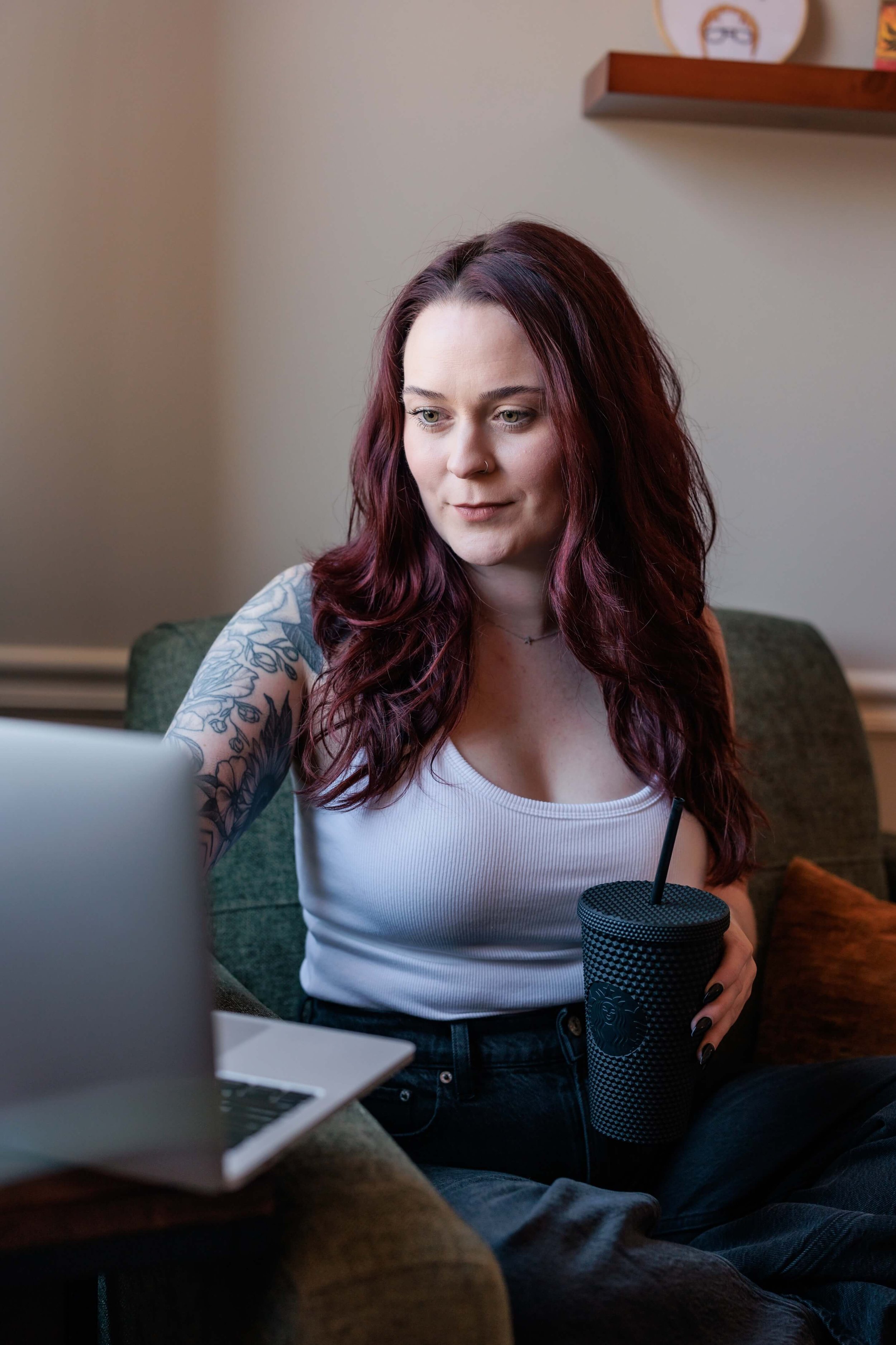 Kaylie looks at a laptop, holding a water cup.