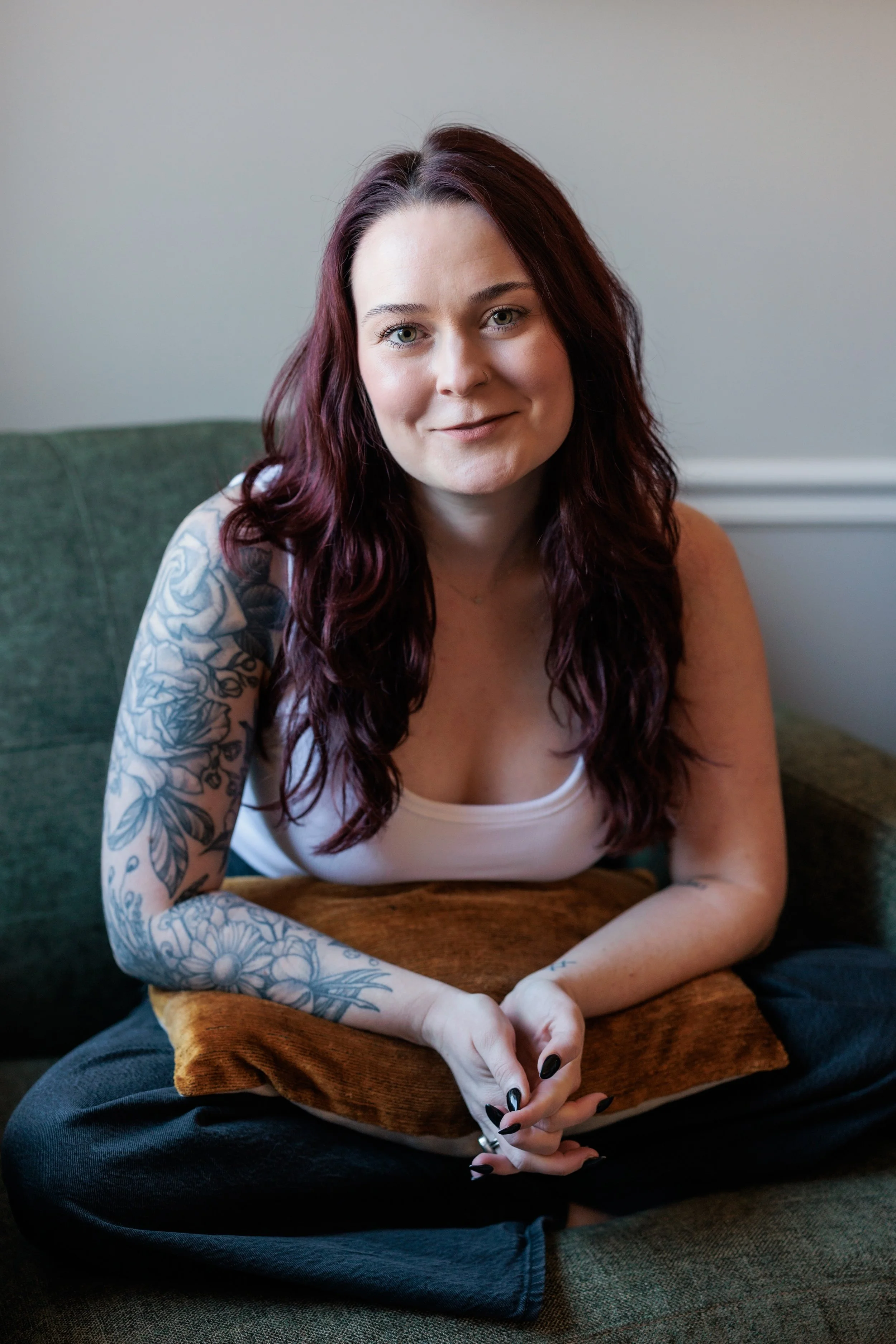 Kaylie sits in an armchair, curled up with a pillow.