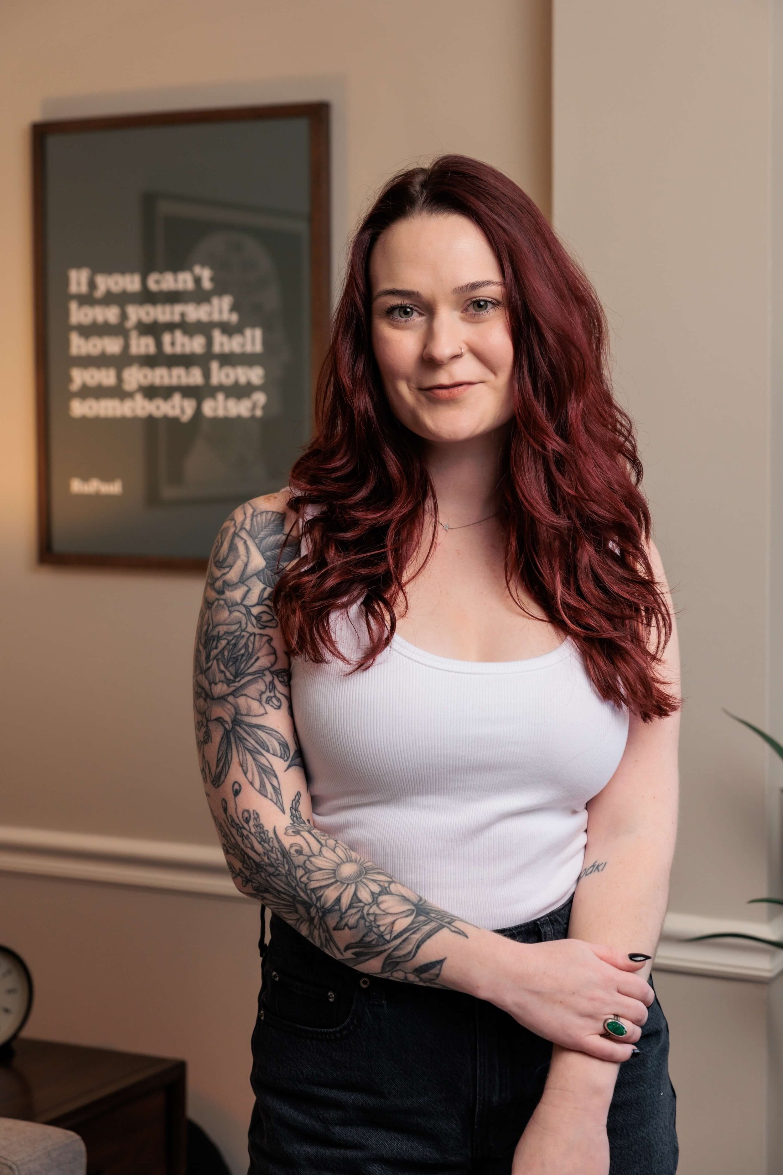 Kaylie stands in a white tank top, clutching one wrist.