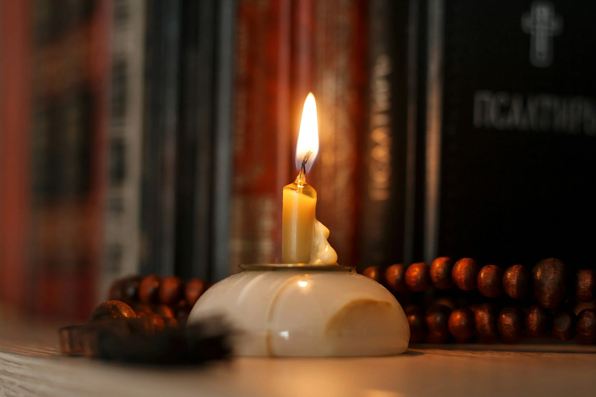 A burning candle on a bookshelf.