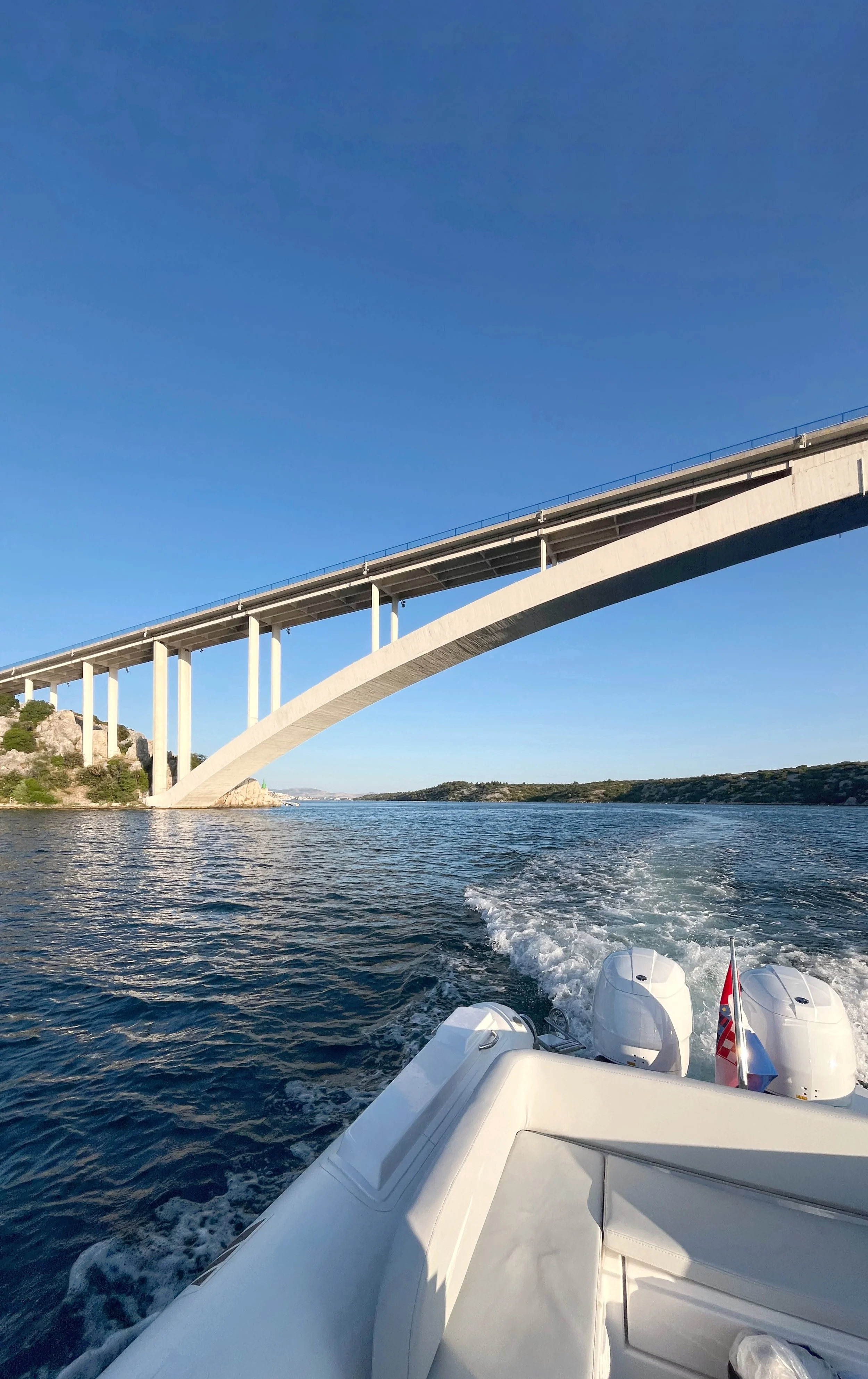 Boat cruising under the Sibenik bridge through Sibenik channel, next to mussels stops, Vidrovaca restaurant (Vidrovača).