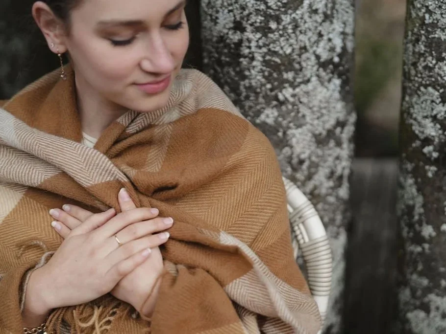 young lady sitting on chair outside wrapped in blanket