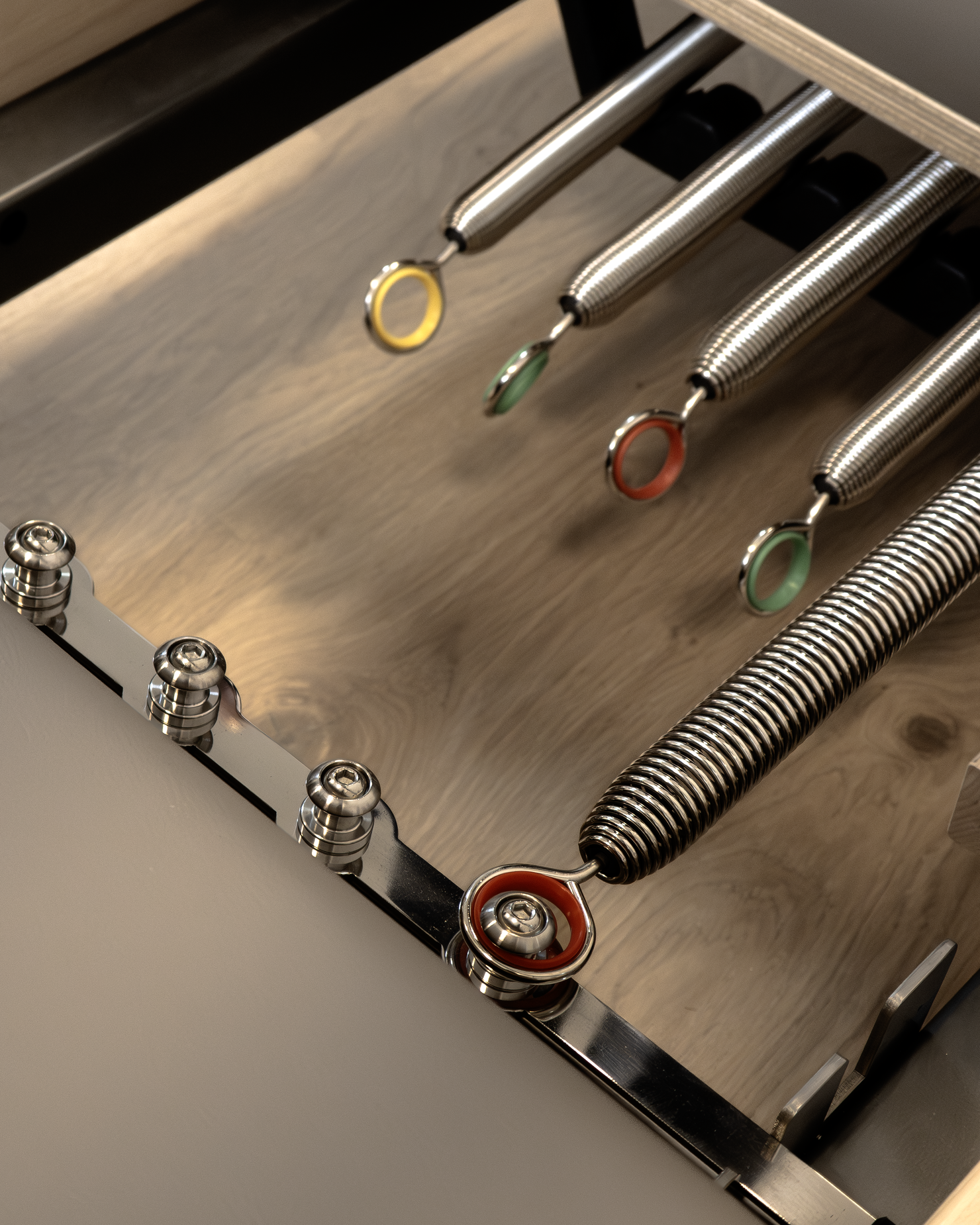 Close-up of reformer springs with colored rings, above wooden floors.  in a premium reformer pilates studio in Rijeka, Croatia