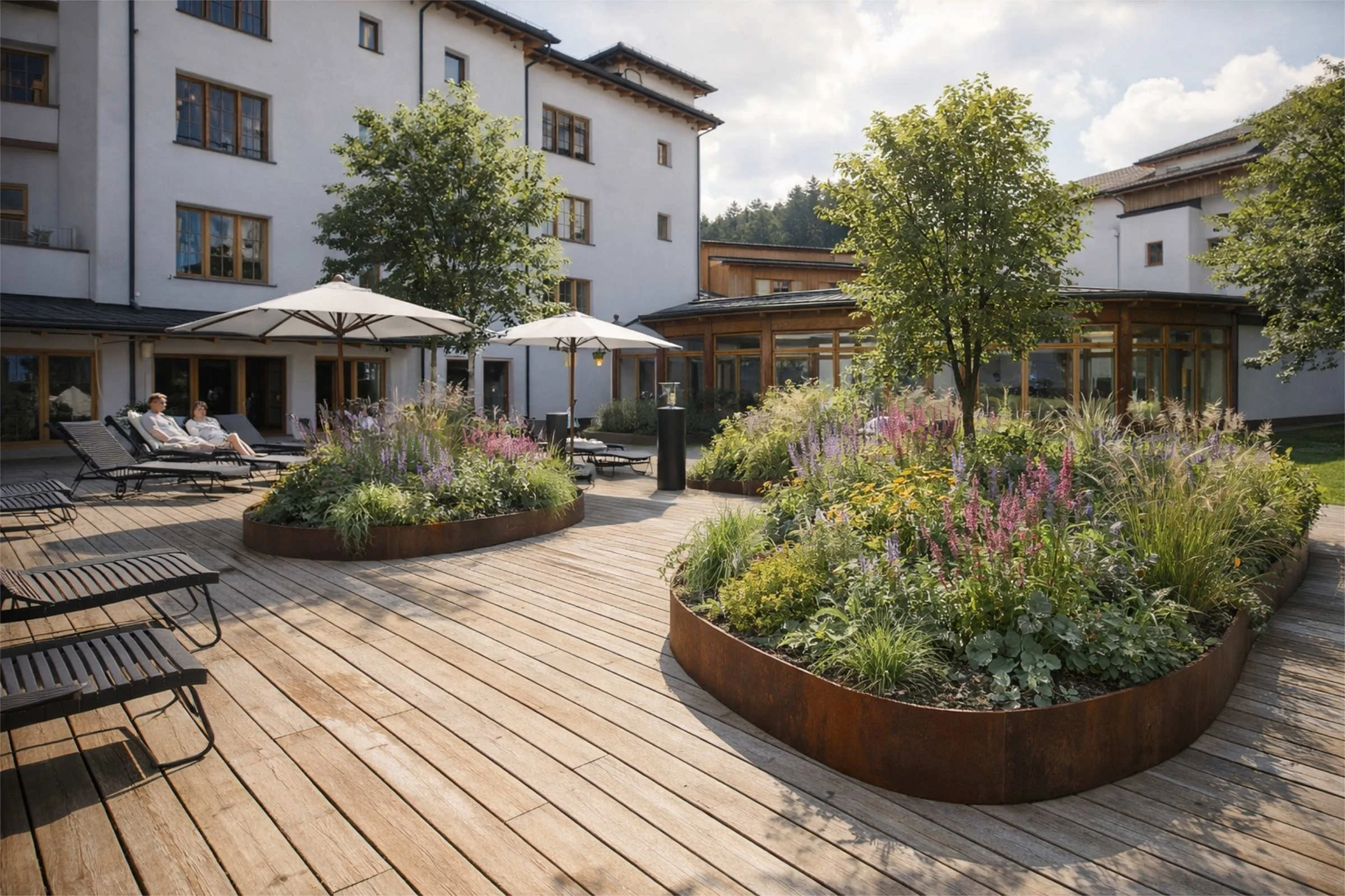 Hotelgarten mit grosser Holzterrasse und integrierten Pflanzinseln, Bäumen und Liegestühlen