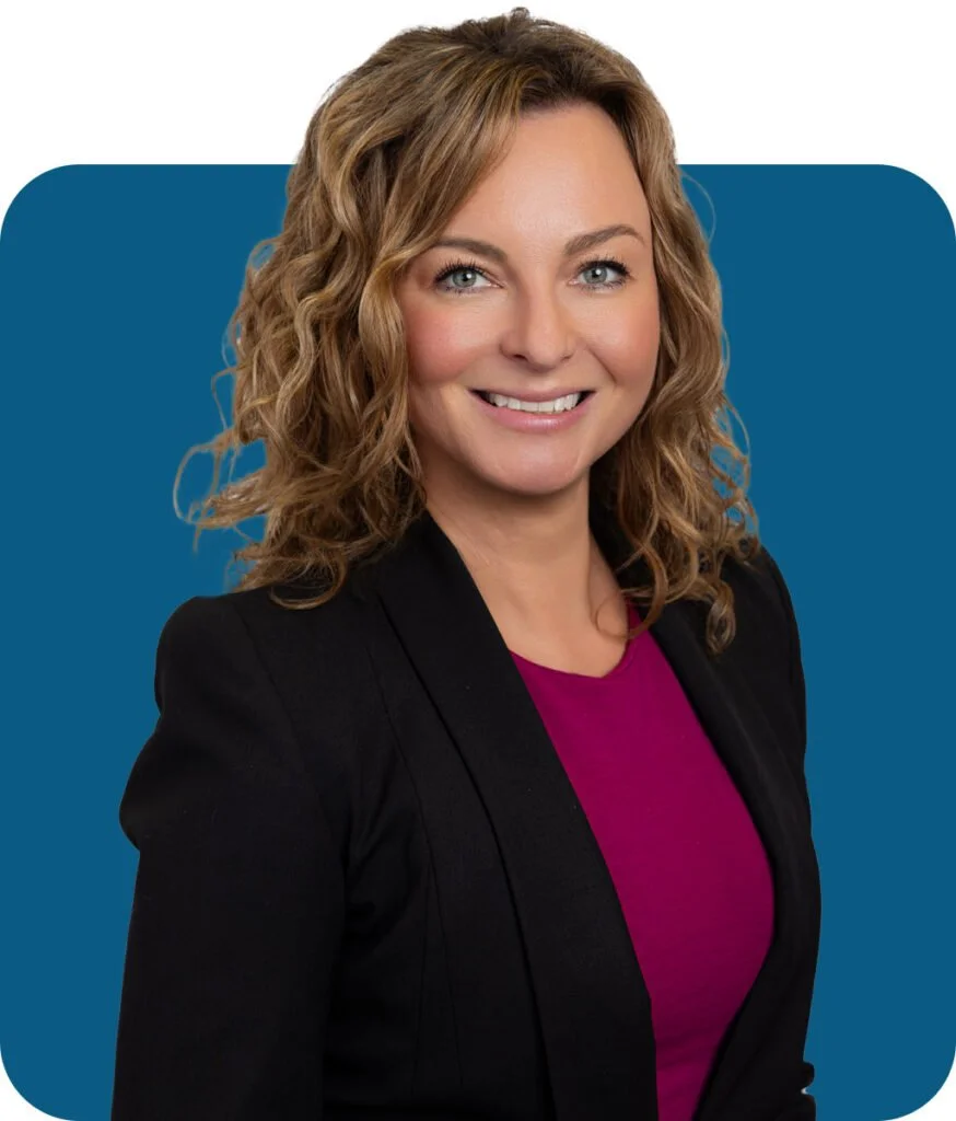 Professional woman with curly light brown hair smiling against a blue background, wearing a black blazer and magenta top.