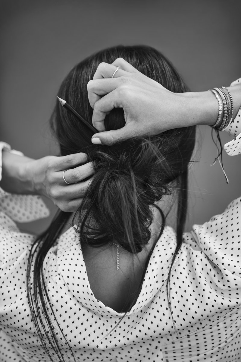 Frauenportrait von Hinten steckt sich einen Stift in die Frisur