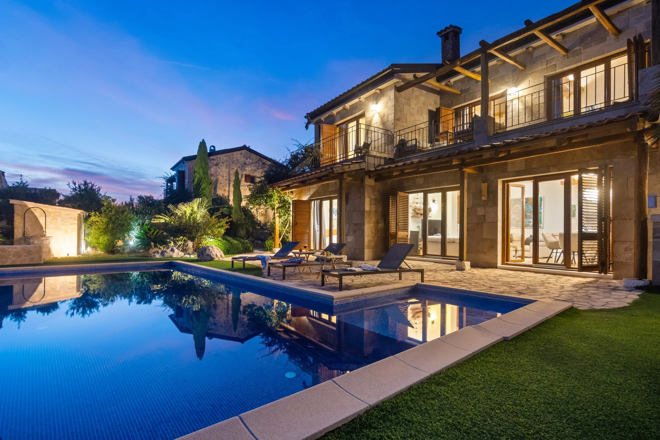 Ležaljke uz bazen s pogledom na more uz zalazak sunca