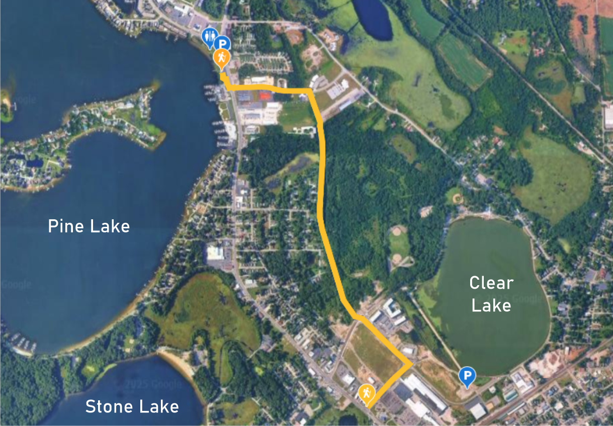 Satellite map showing a walking route between Pine Lake and Clear Lake with parking and walking icons at the start and end points.