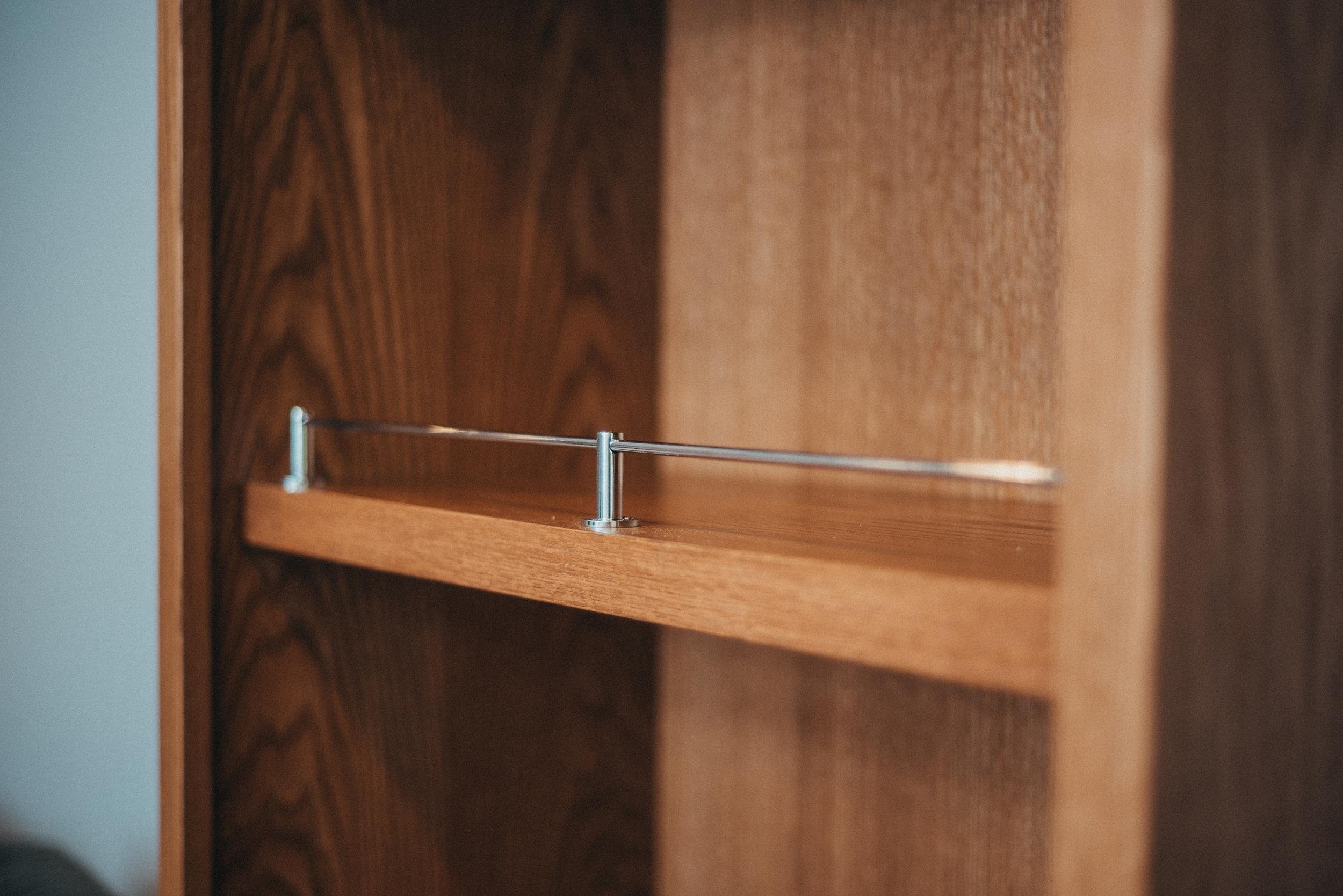 Empty wooden bookshelf with a metal support rod inside.