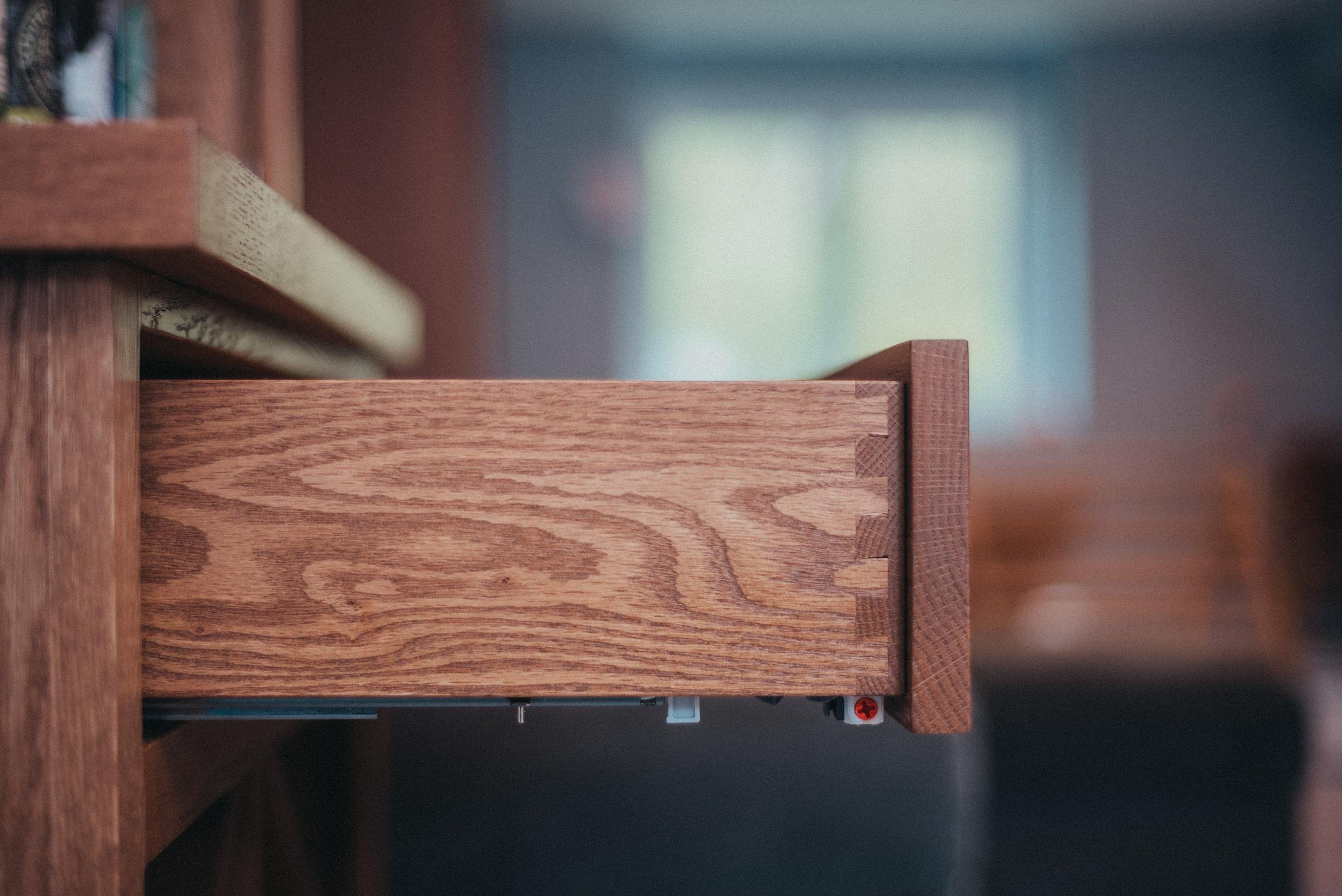 Close-up of a wooden drawer partially pulled out from a wooden desk or cabinet