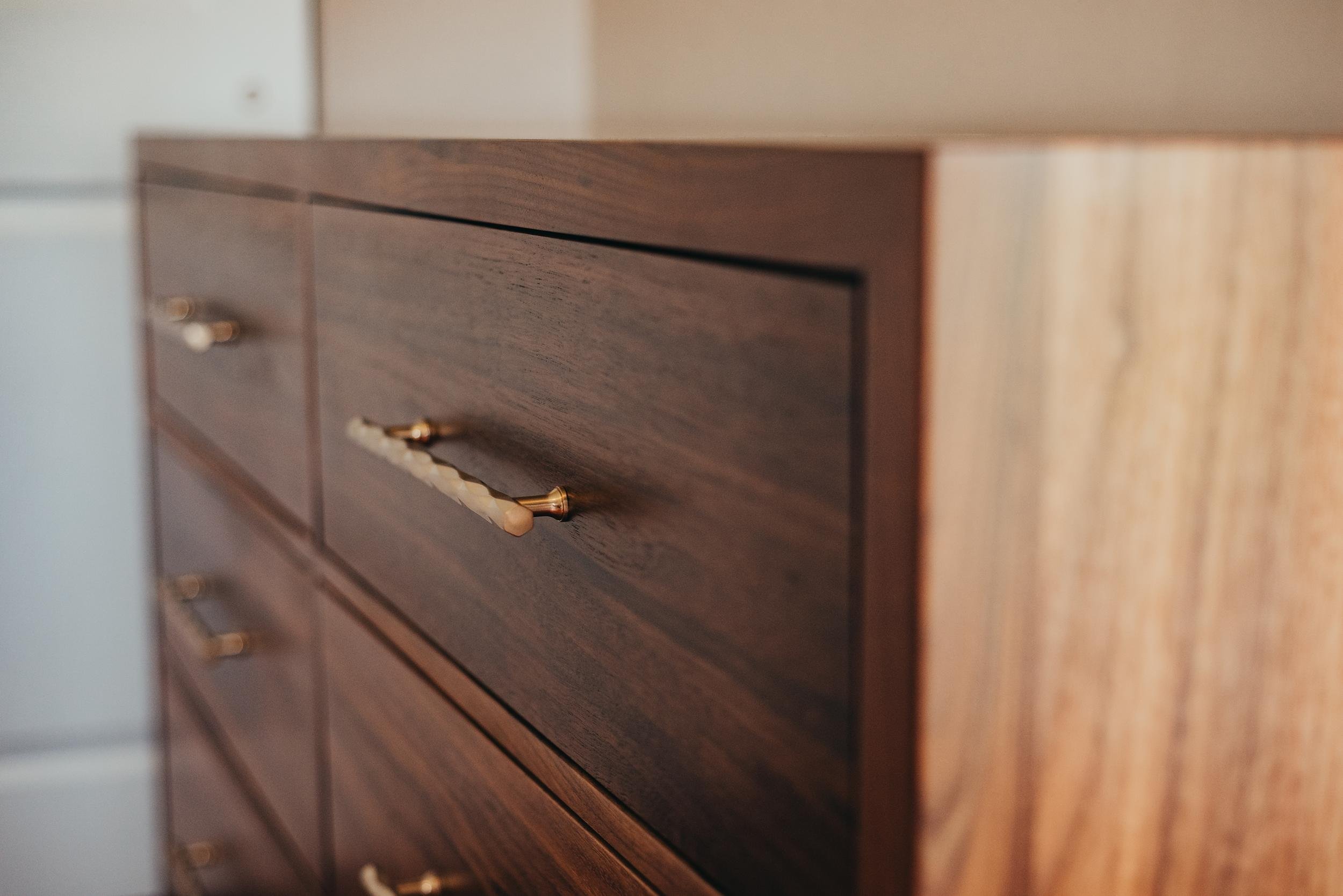 Close-up of a wooden dresser with gold and white marble handle on the drawer.